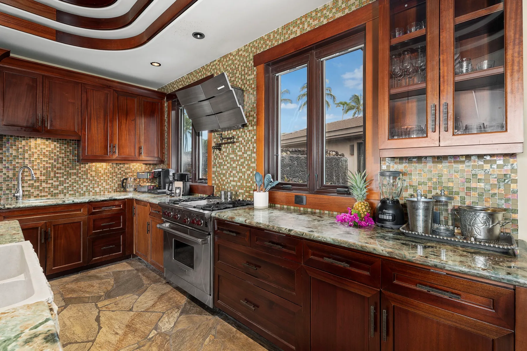 Una cocina con gabinetes de madera oscura, encimeras de piedra y una ventana sobre el fregadero.