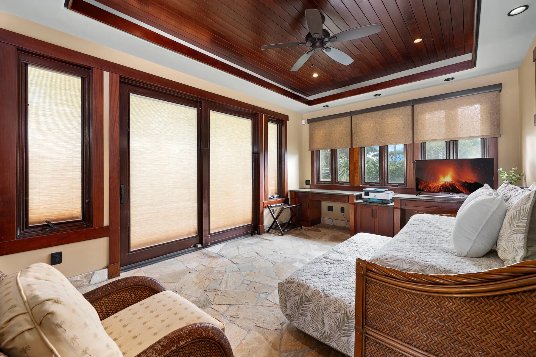 Un dormitorio con una cama junto a grandes ventanas y un techo de madera.