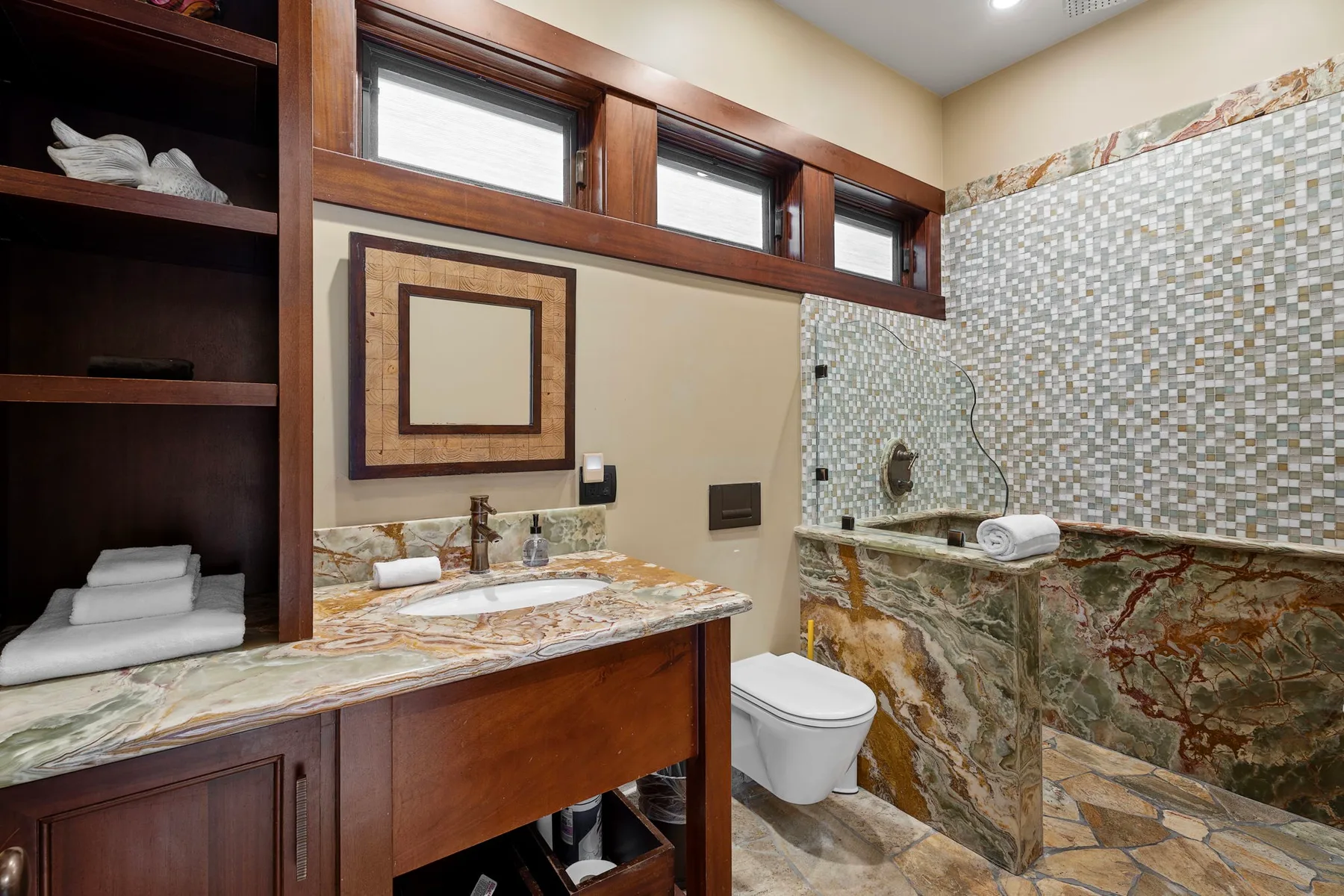 Un baño con mueble de madera, inodoro y zona de ducha con azulejos.