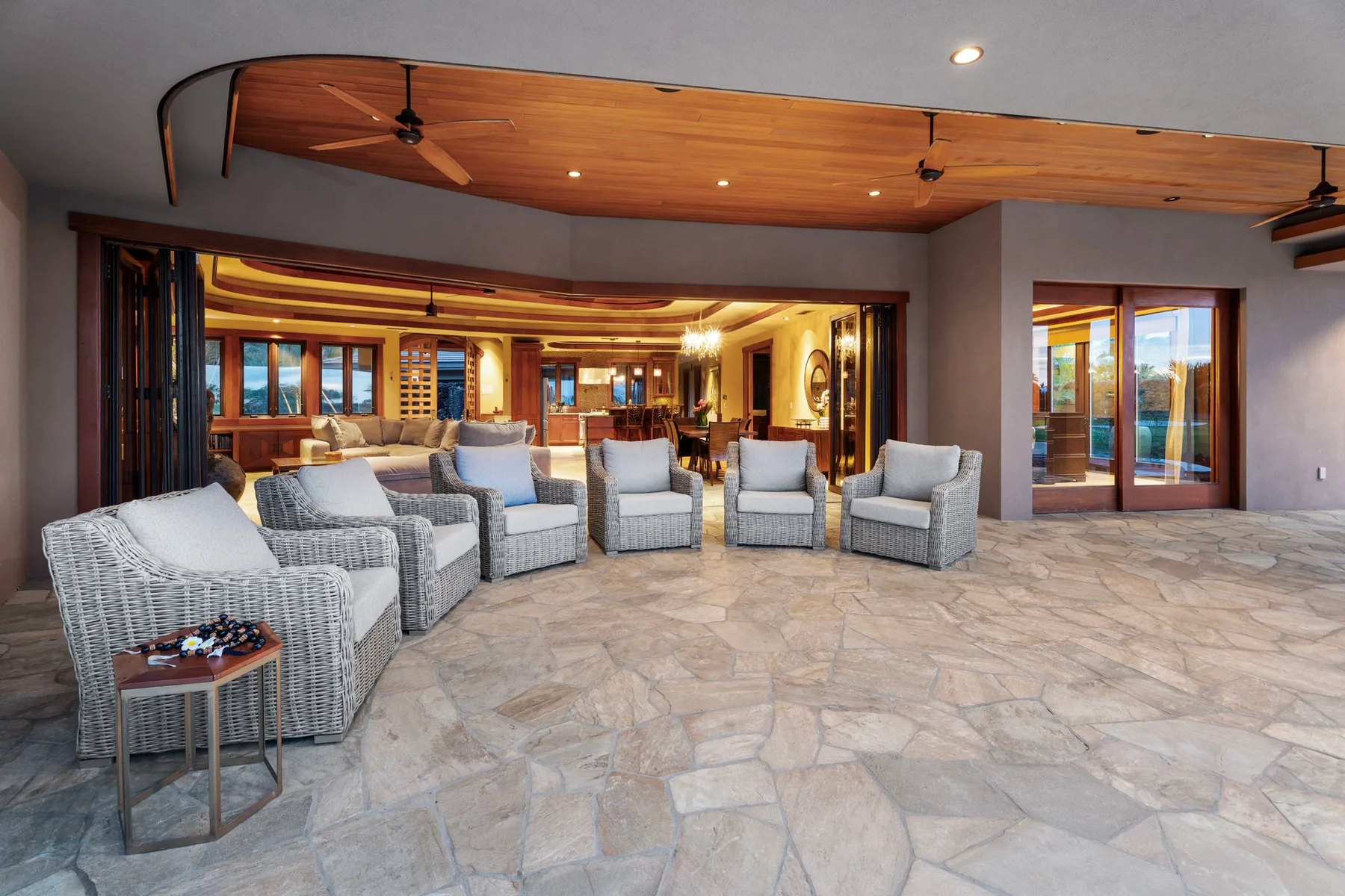 Un patio cubierto amplio con asientos acolchados y techo revestido de madera.