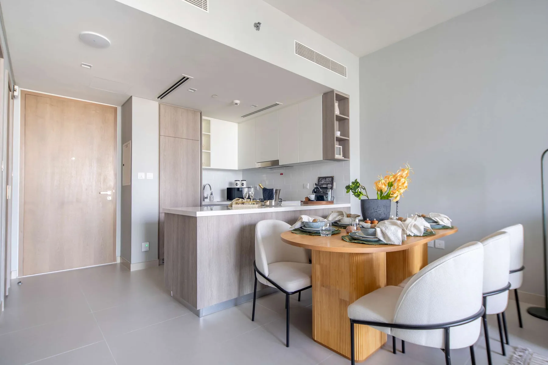 Un comedor luminoso con una mesa de madera y una cocina abierta al fondo.