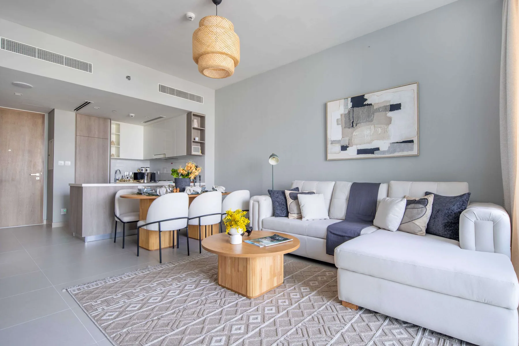 Una sala luminosa con sofá seccional y cocina abierta.