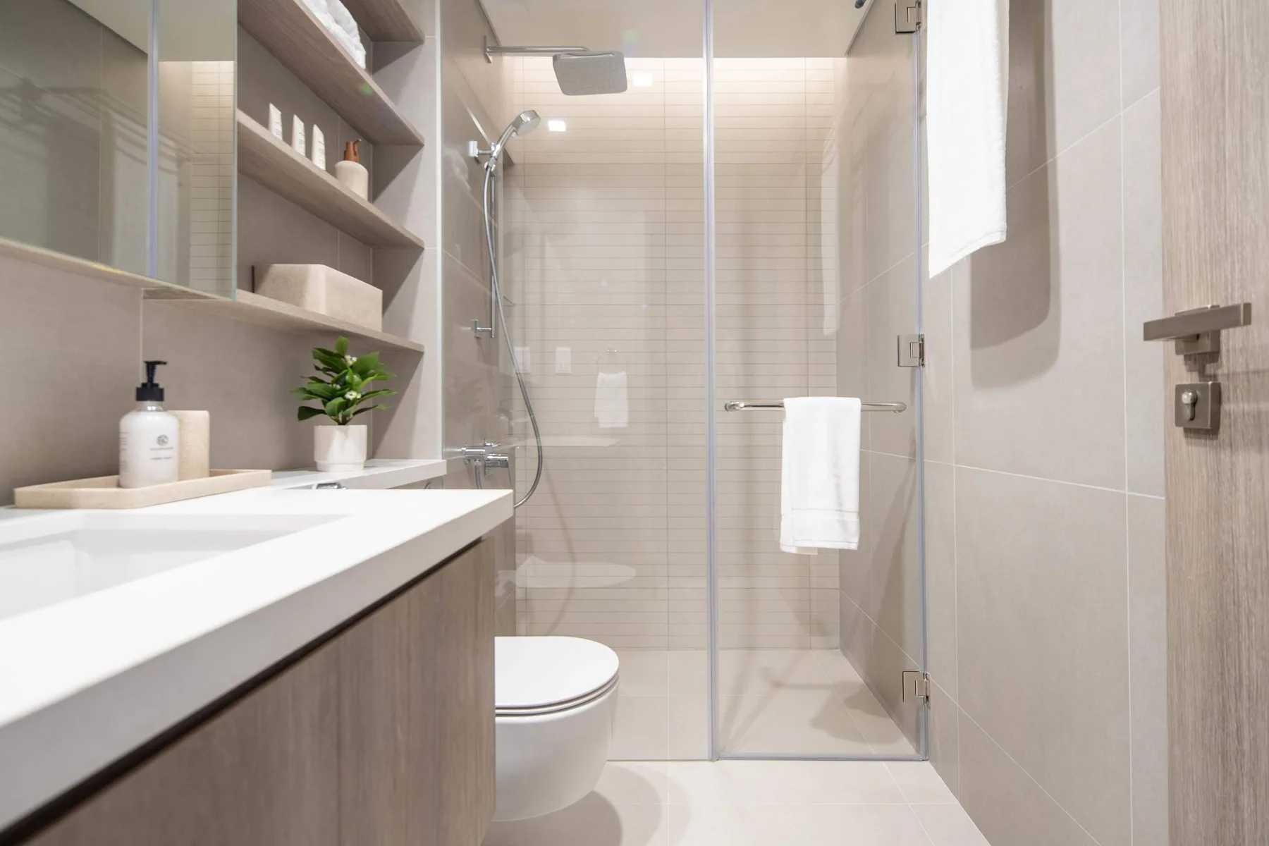 Un baño luminoso con lavabo, ducha de vidrio e inodoro.