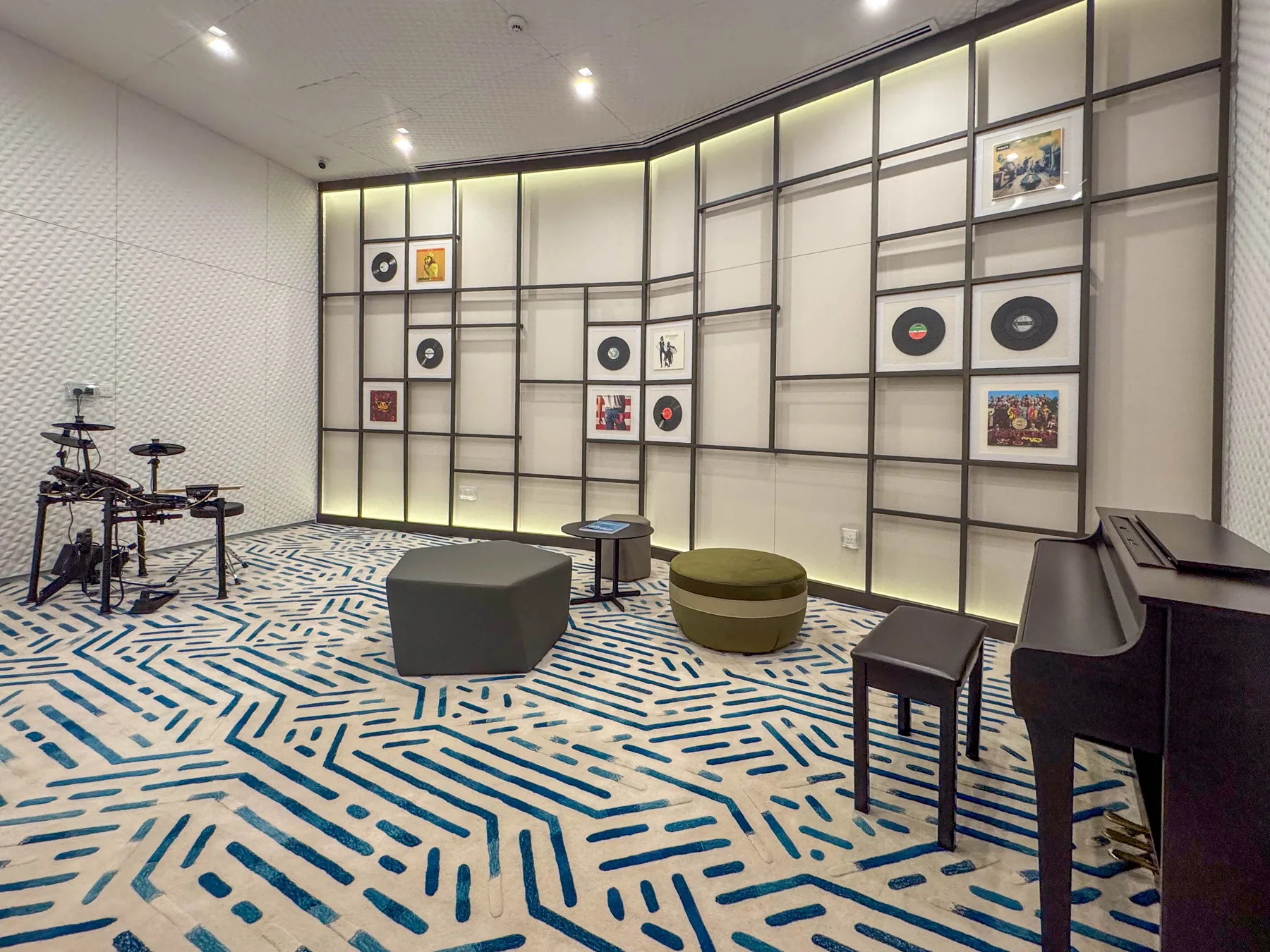 Una sala de música con batería, piano y una alfombra estampada.