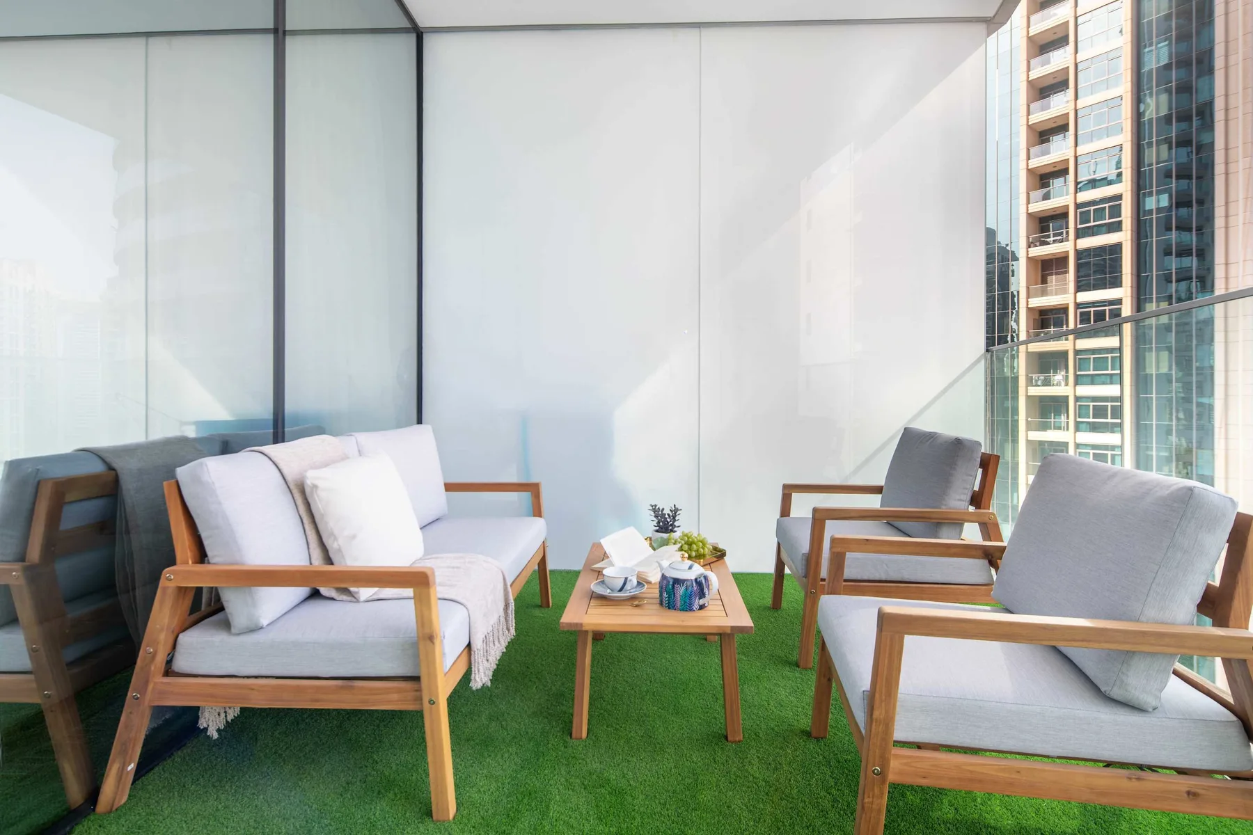 Una zona de estar en un balcón con sillas de madera y una mesa pequeña.
