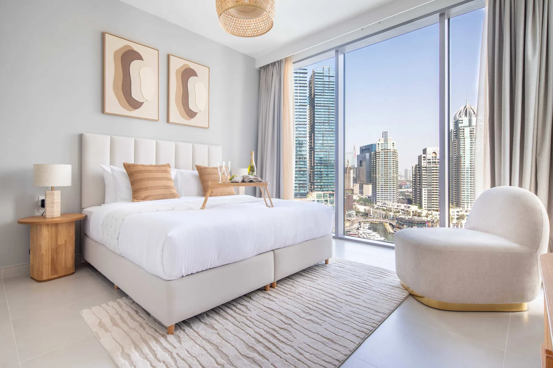 Un dormitorio luminoso con una cama bien hecha y grandes ventanas con vistas a la ciudad.