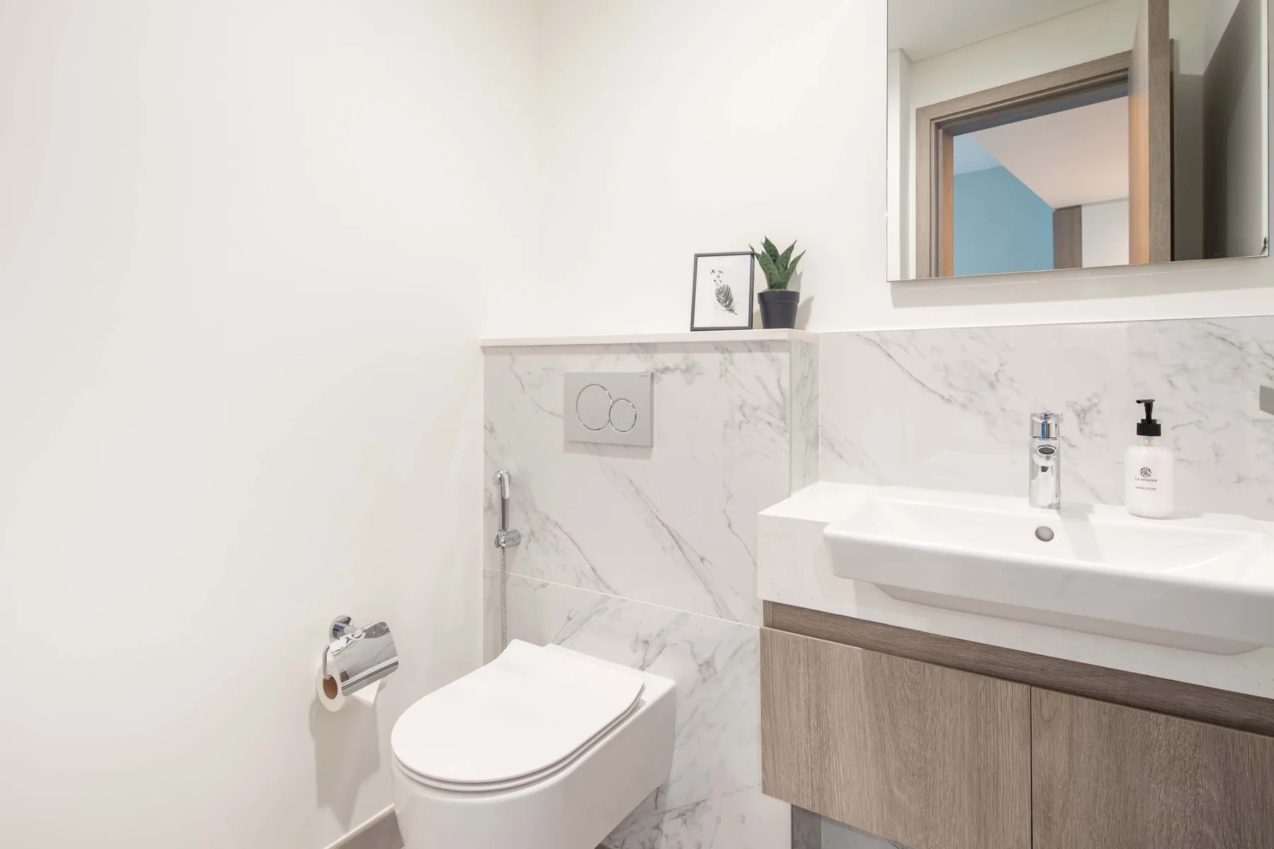 Un baño luminoso con inodoro, lavabo y espejo de pared.