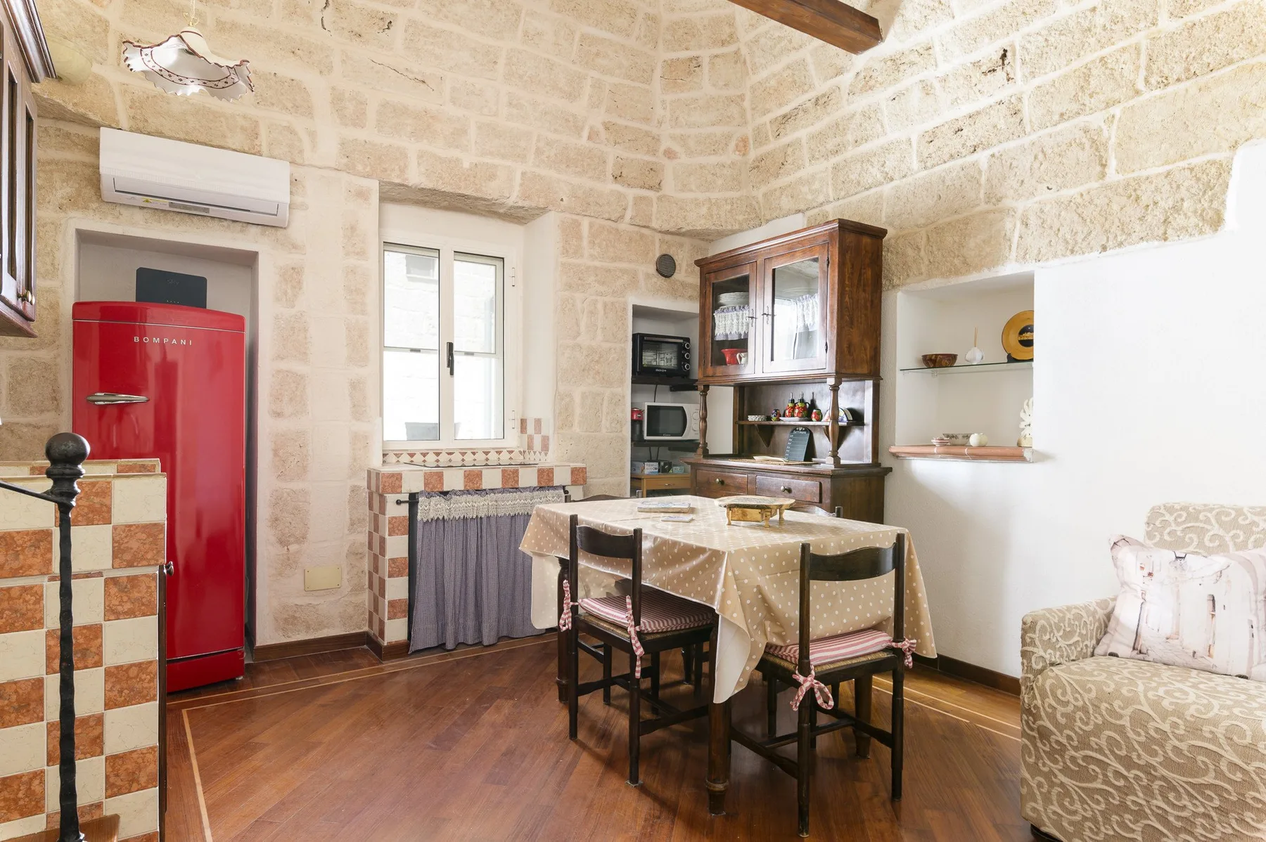 Un comedor con una mesa y sillas junto a un refrigerador rojo y armarios de cocina.