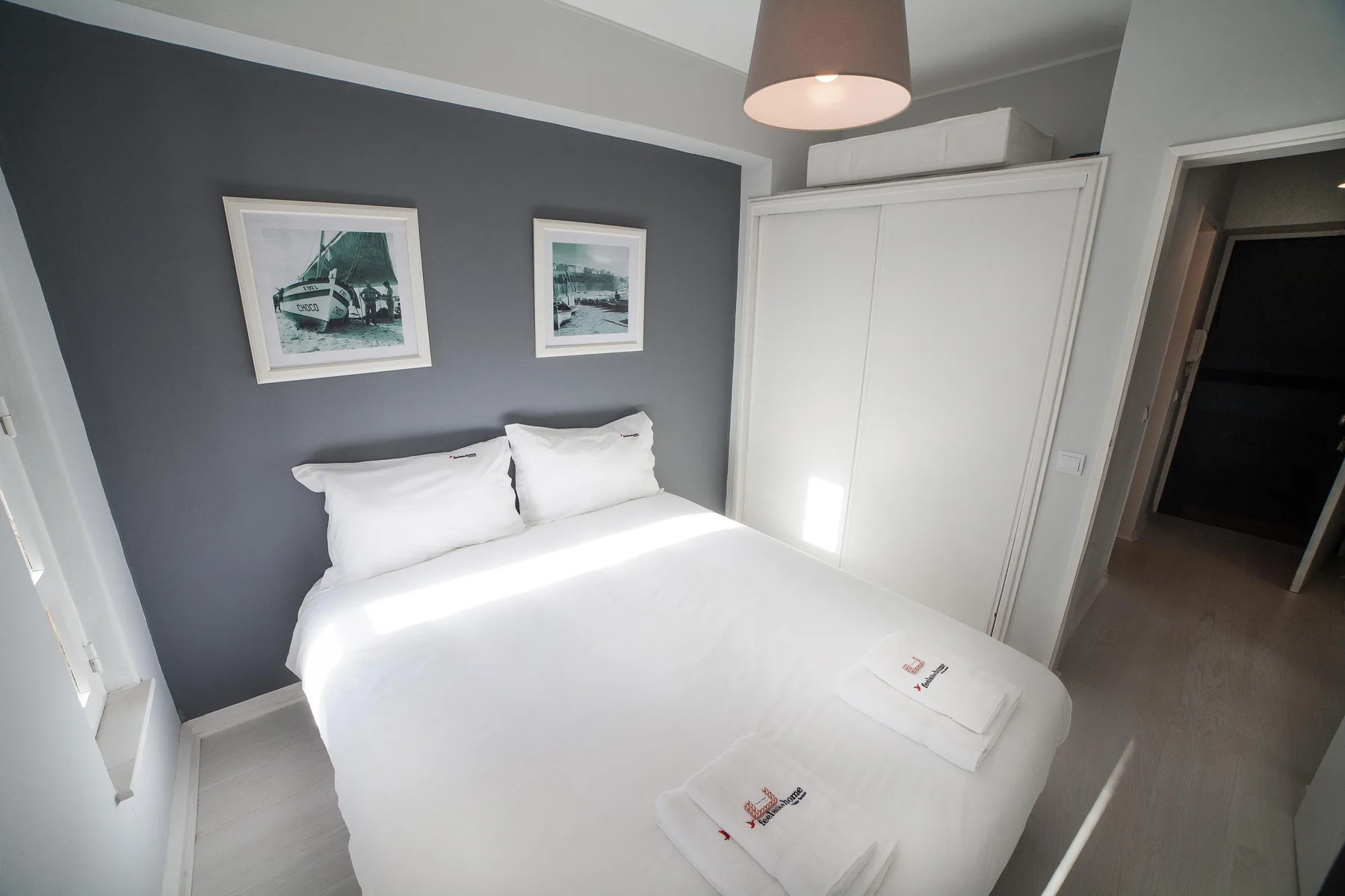A bedroom with a neatly made bed and framed pictures on the wall.