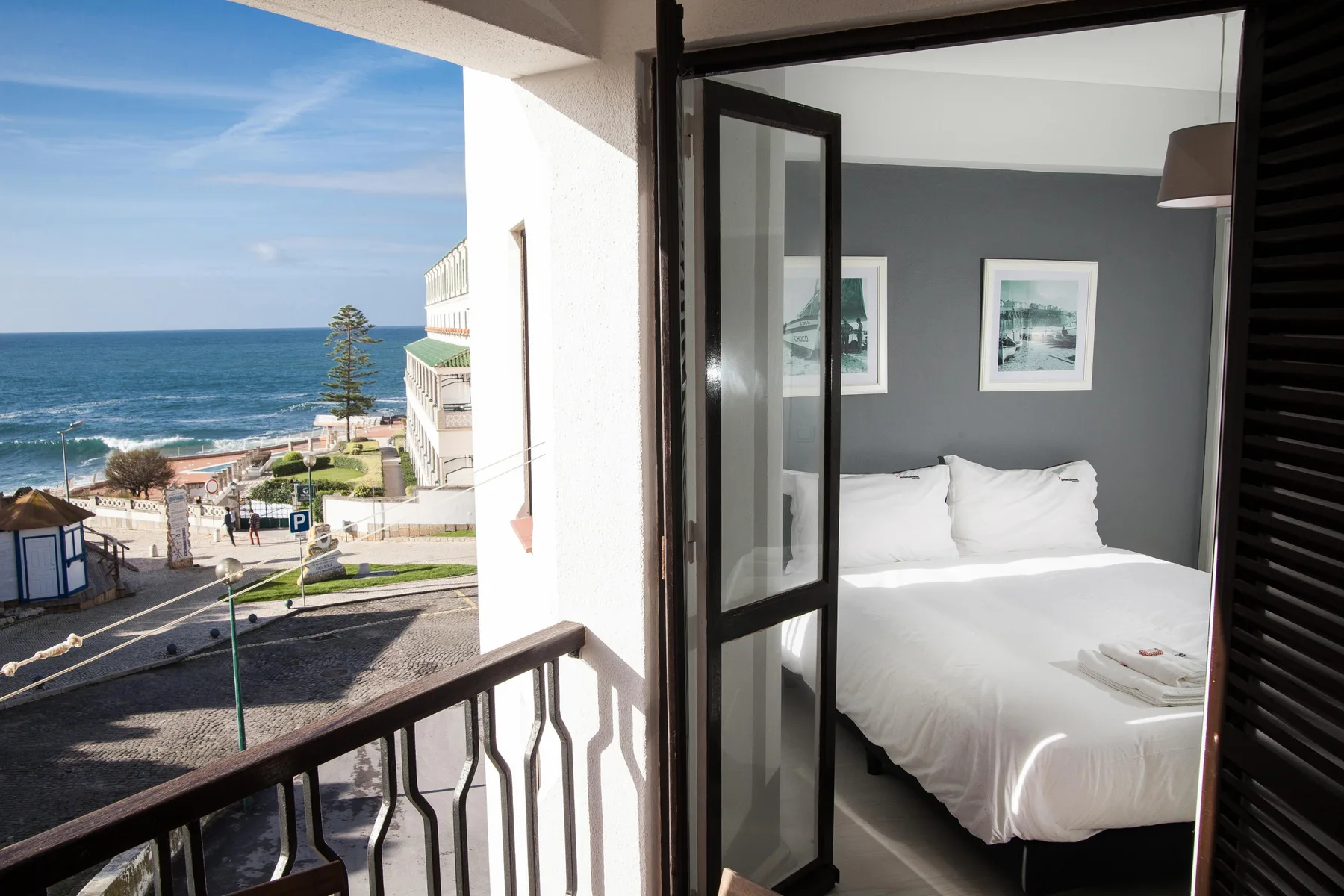 Un dormitorio con una cama blanca da a un balcón con vistas al océano.