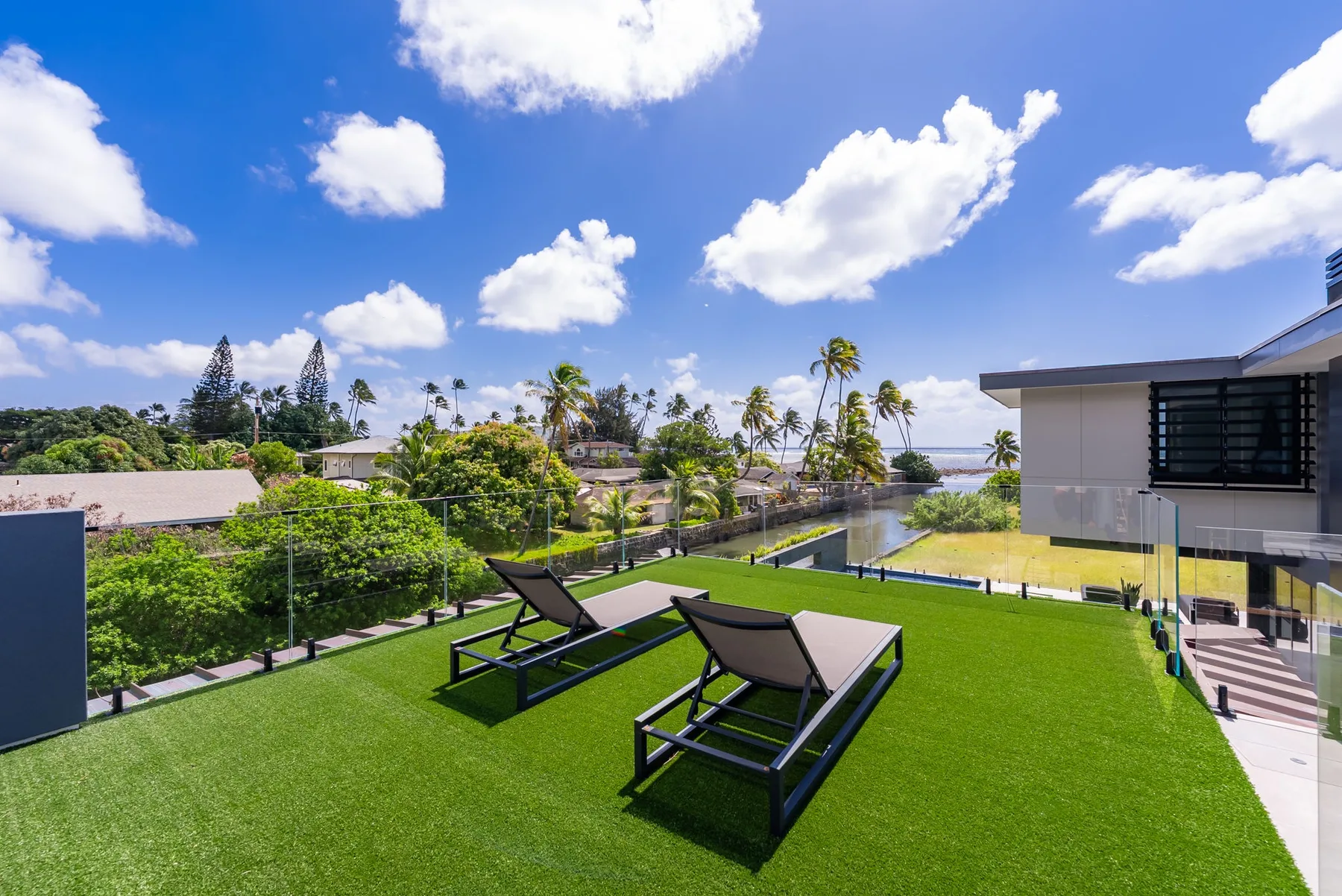 Una terraza en la azotea con asientos de descanso da a zonas verdes y palmeras lejanas.