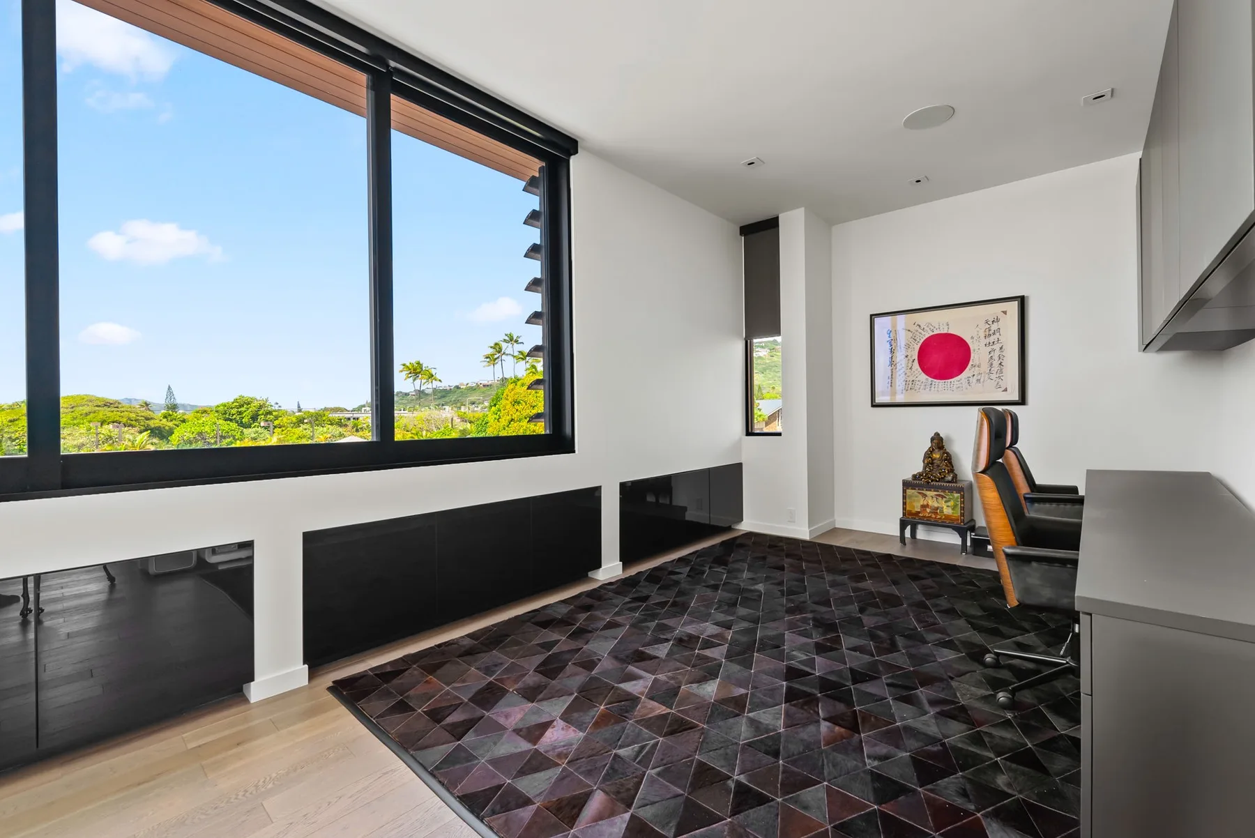 Interior moderno con grandes ventanas, un escritorio y una alfombra oscura estampada.