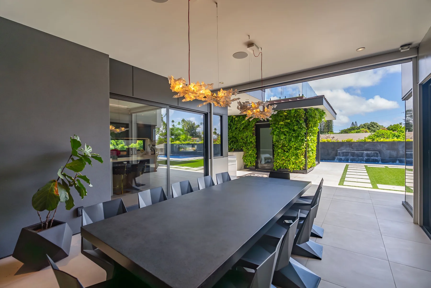 Un comedor moderno se abre a un patio ajardinado a través de grandes puertas de vidrio.