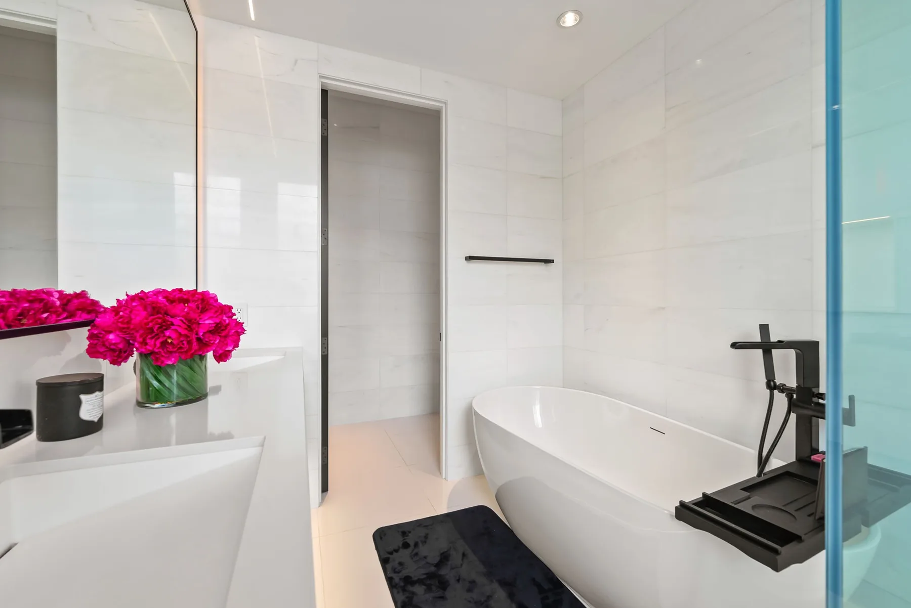 Un baño luminoso con bañera, lavabo y flores.