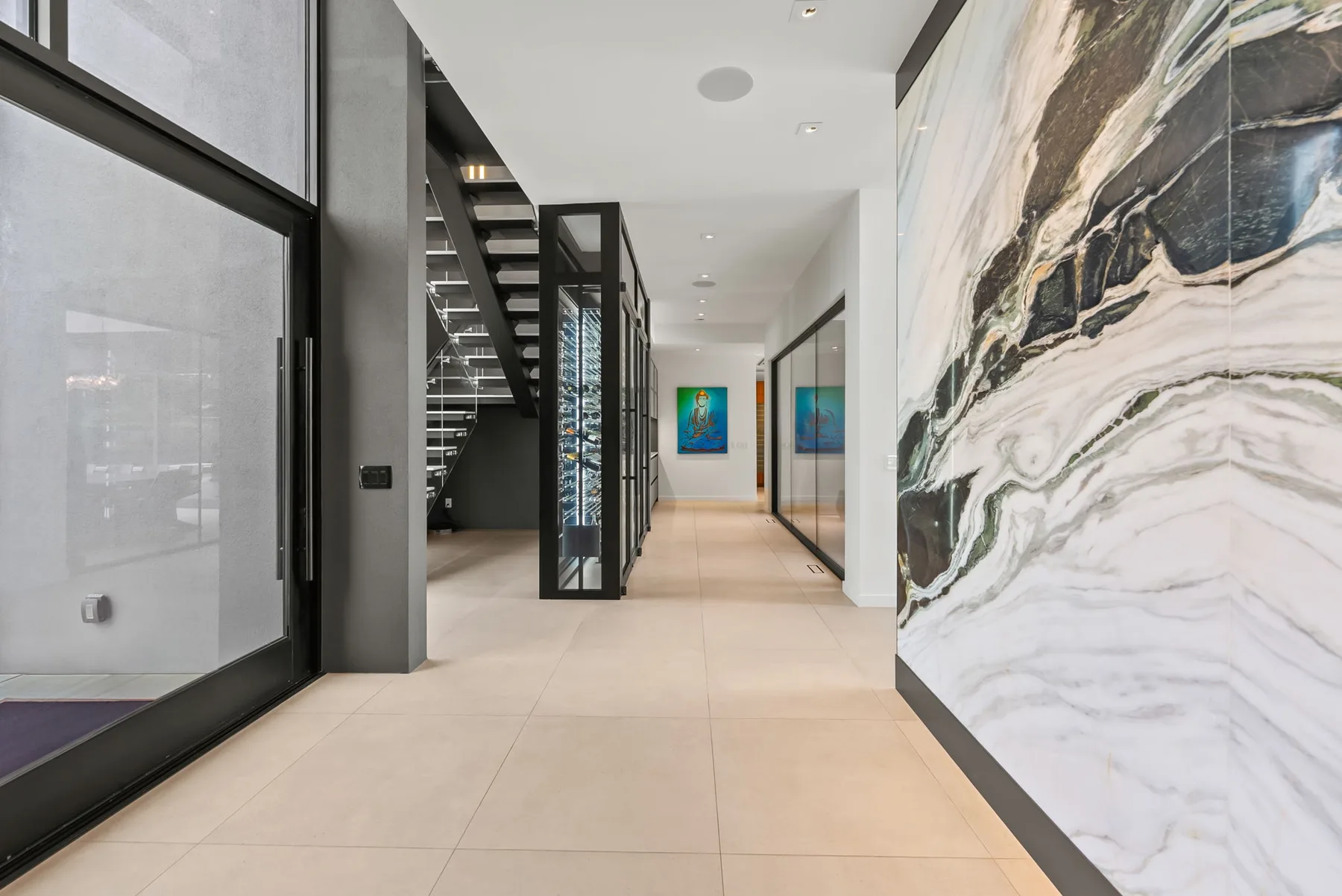 Un pasillo interior moderno con una escalera y obras de arte coloridas en las paredes.