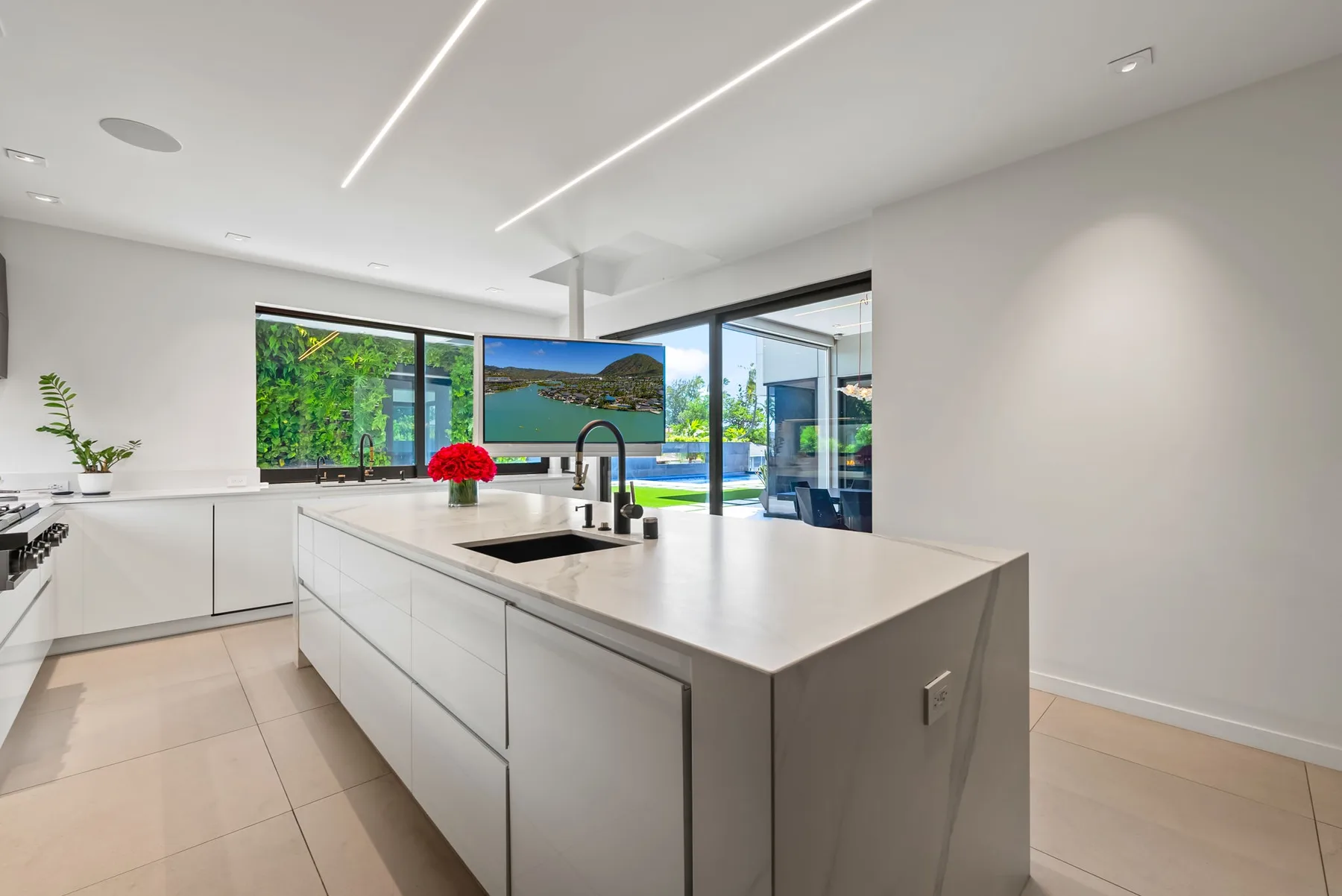 Una cocina moderna con una gran isla y ventanas con vistas a la vegetación y una piscina.