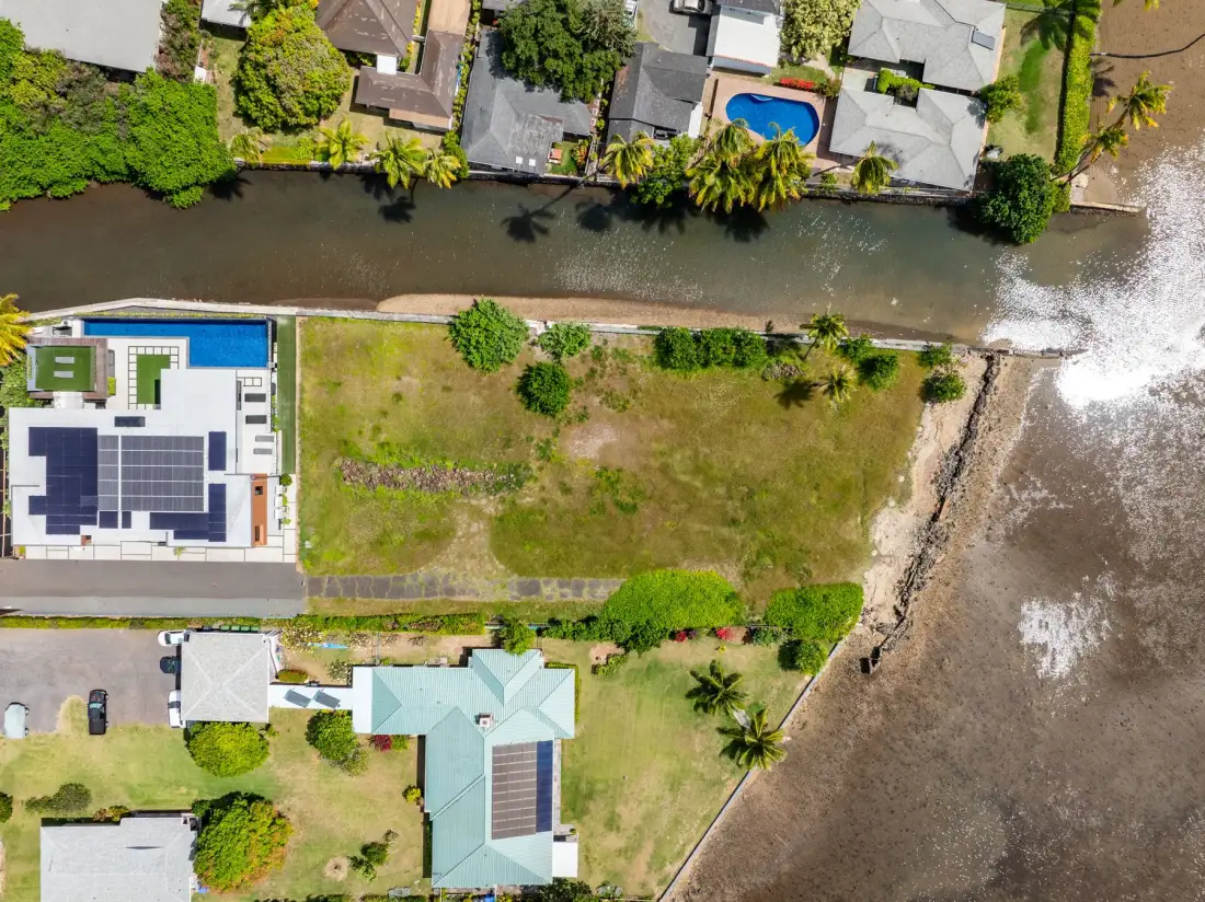 Vista aérea de casas junto a un canal, con una piscina y la orilla.