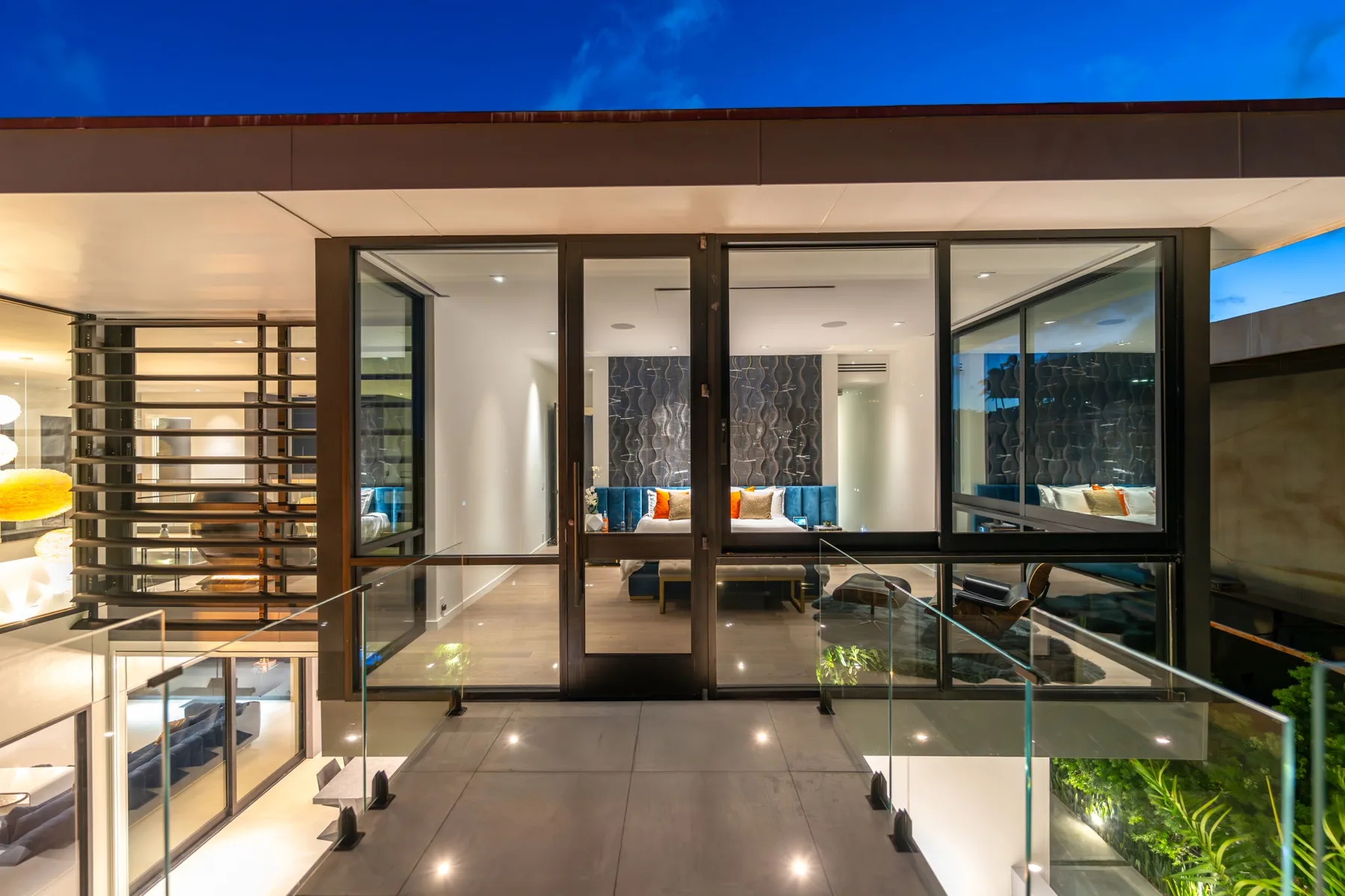 Una sala de estar moderna se abre a una terraza pavimentada mediante puertas de vidrio de piso a techo.