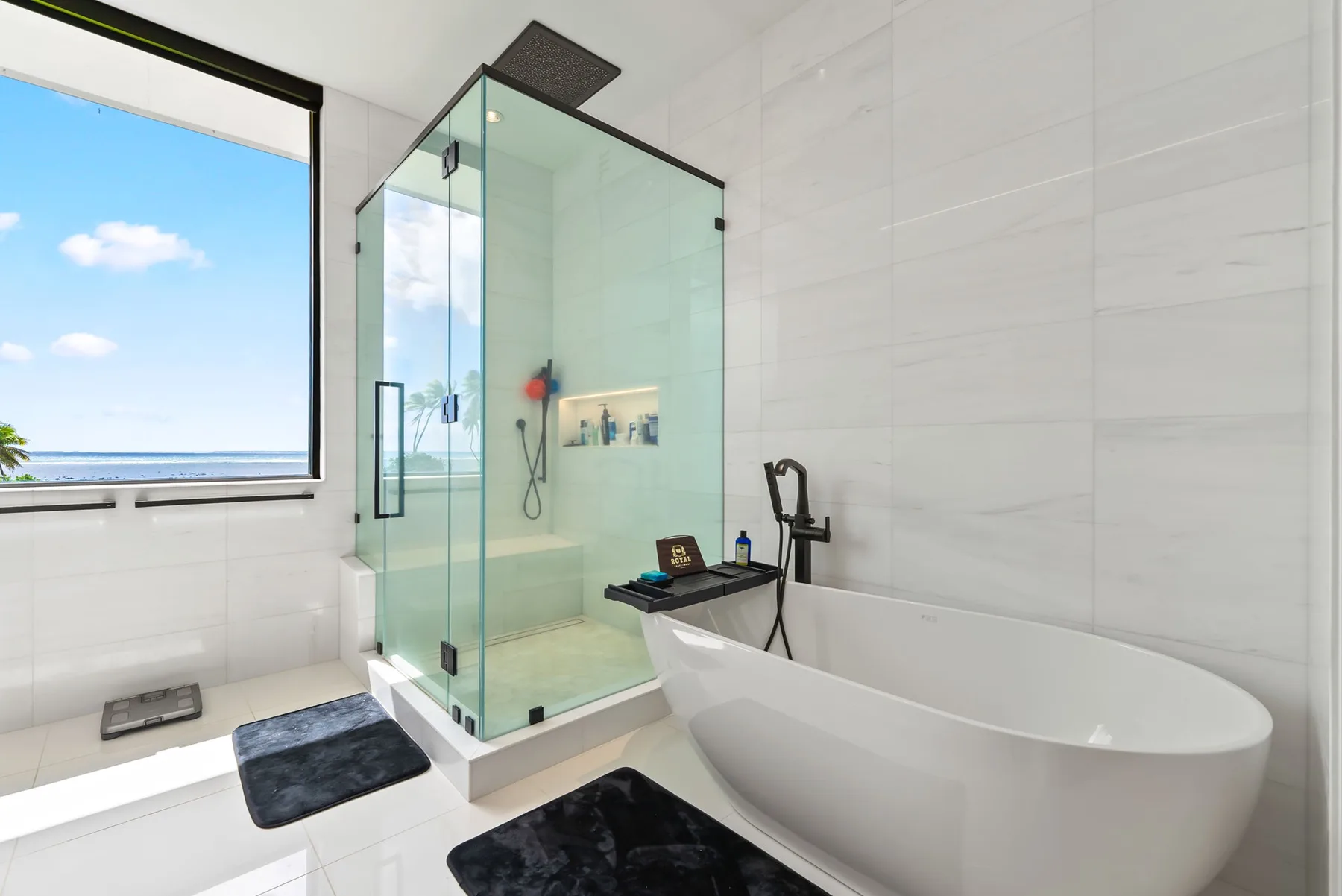 Un baño luminoso cuenta con una ducha de vidrio y una bañera independiente junto a una ventana.