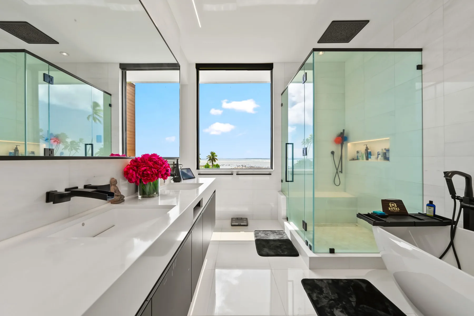 Un baño moderno y luminoso con una ducha de vidrio y una ventana amplia.