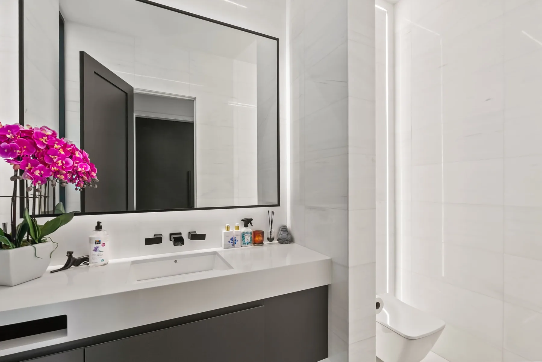 Un baño luminoso con un amplio tocador, espejo de pared y bañera blanca.
