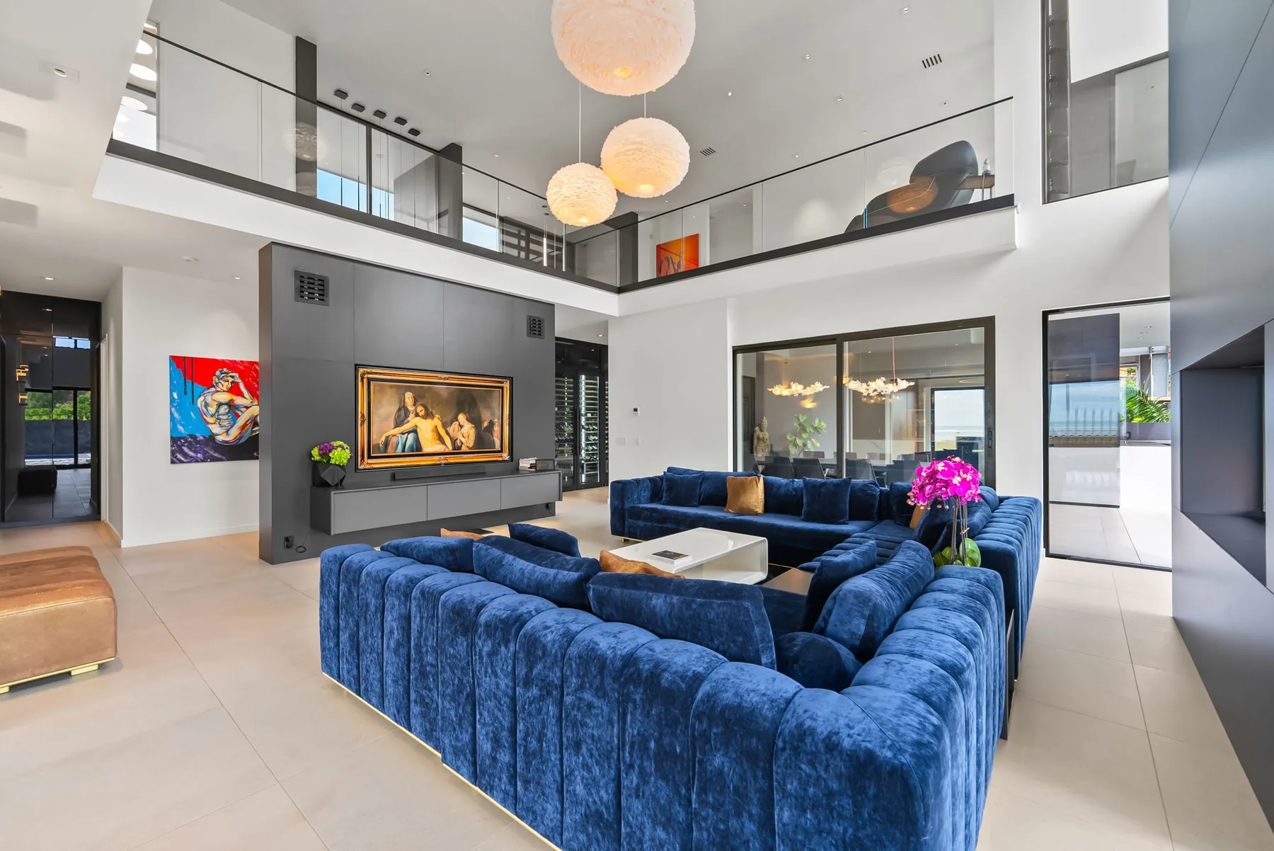 Una sala de doble altura con asientos azules y una mesa de centro.