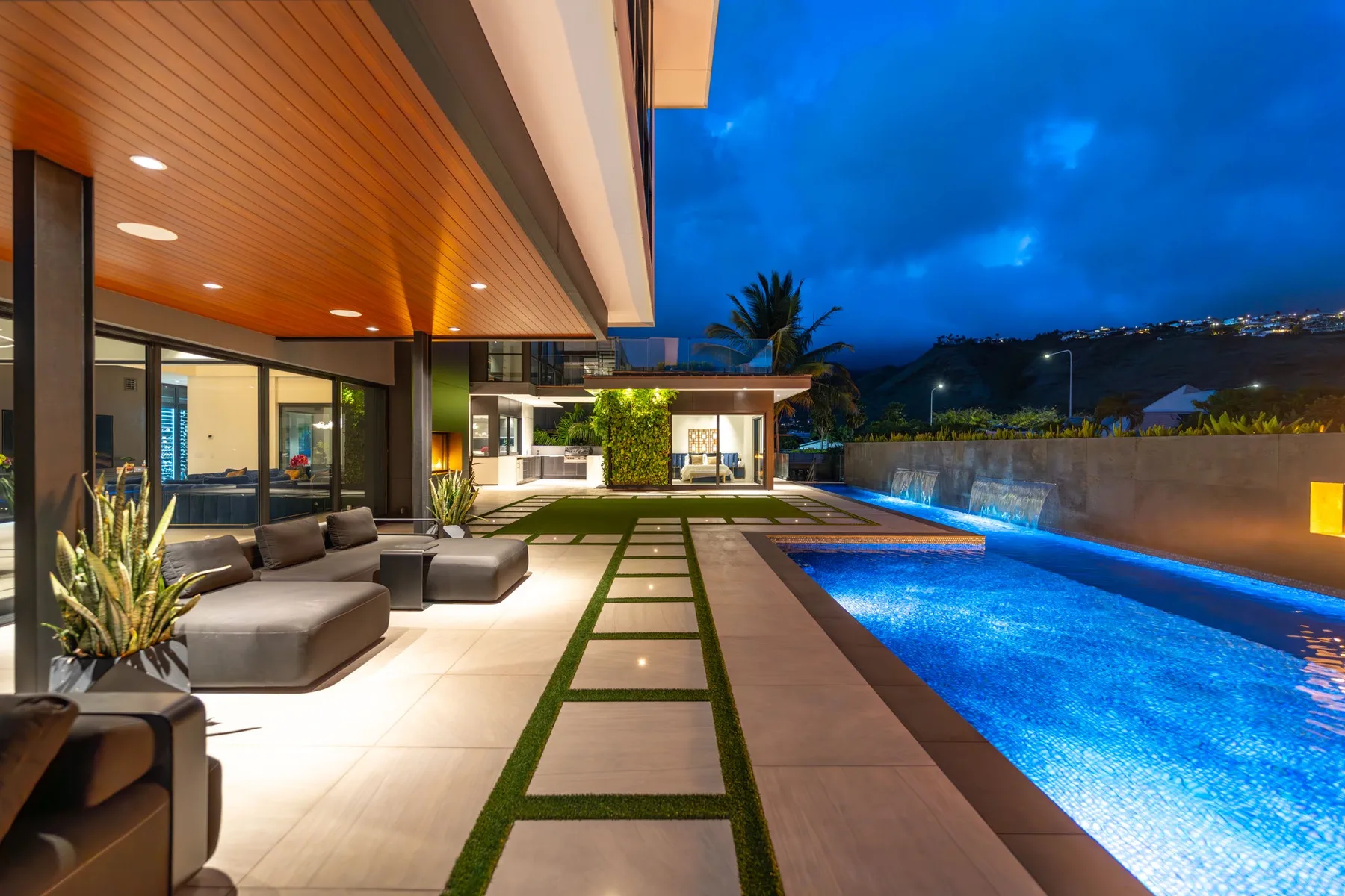 Una moderna zona de piscina al aire libre junto a un patio cubierto al anochecer.