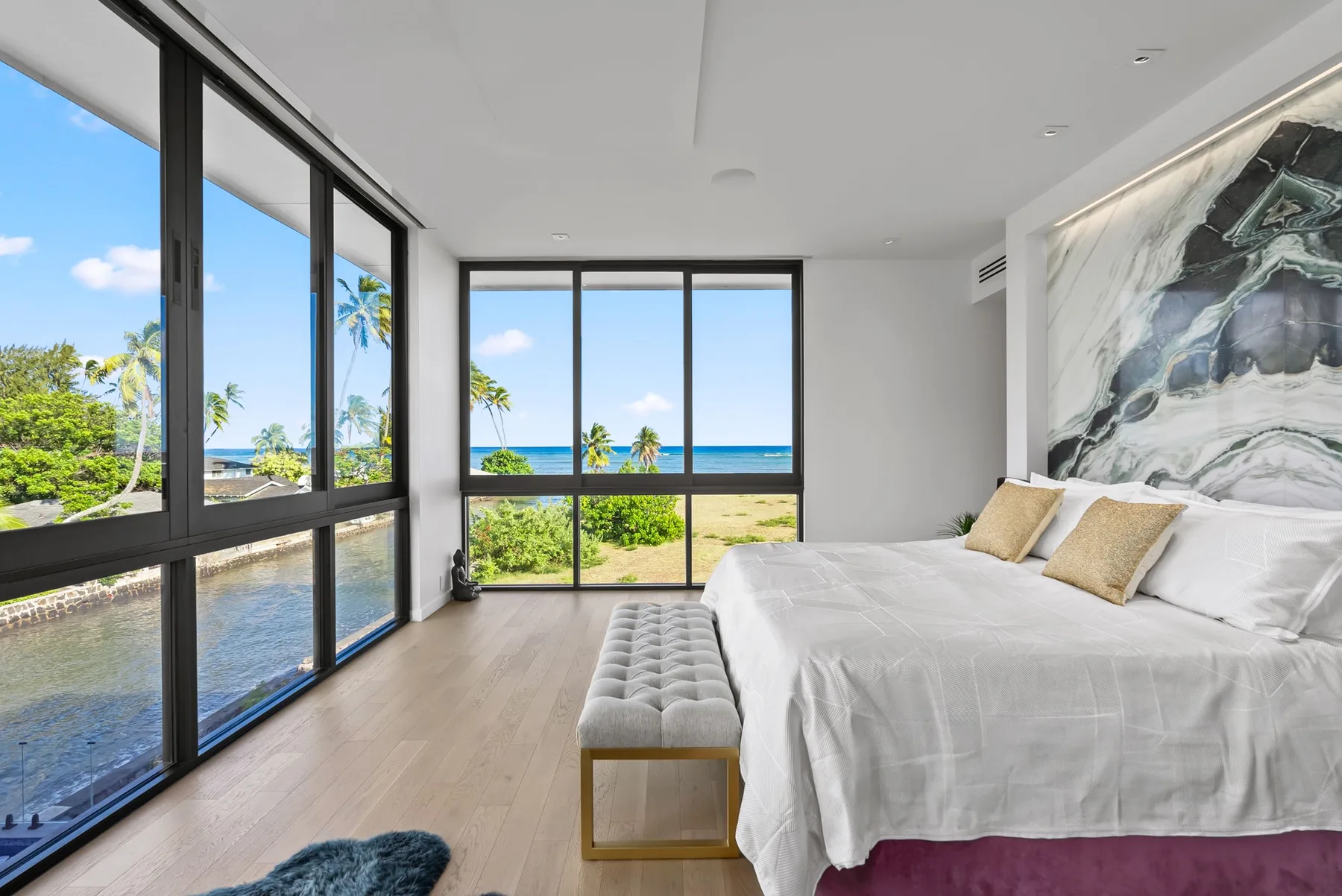 Un dormitorio luminoso con una cama grande junto a ventanales con vistas al océano.