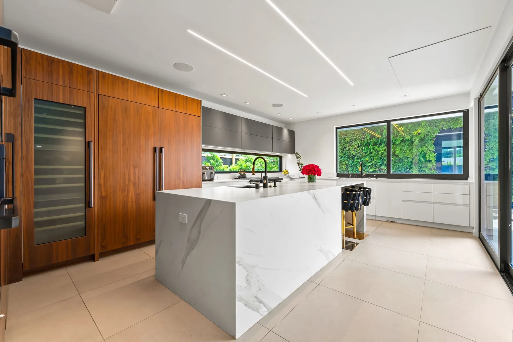 Una cocina moderna con una gran isla y amplias ventanas con vistas a la vegetación.