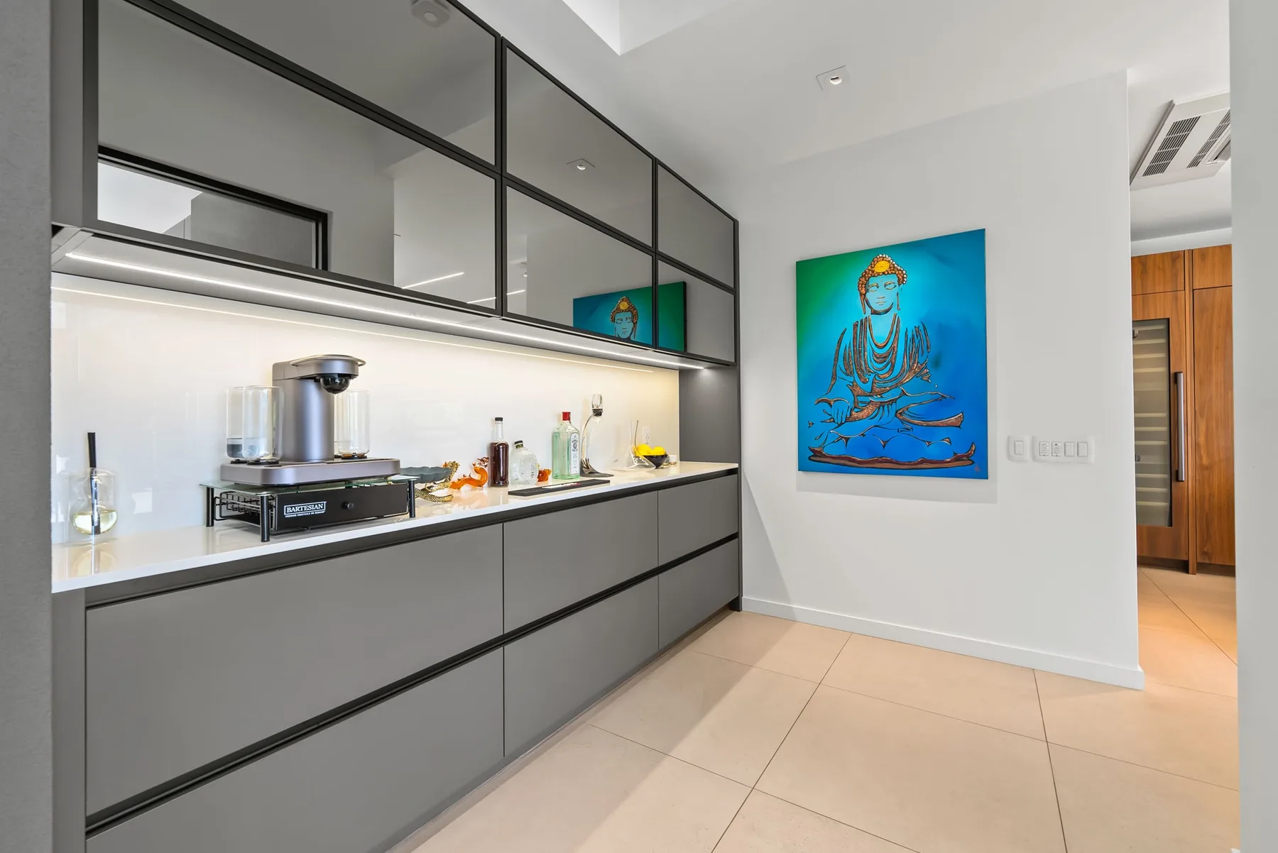 Una cocina moderna con gabinetes grises, una encimera y una pintura colorida en la pared.