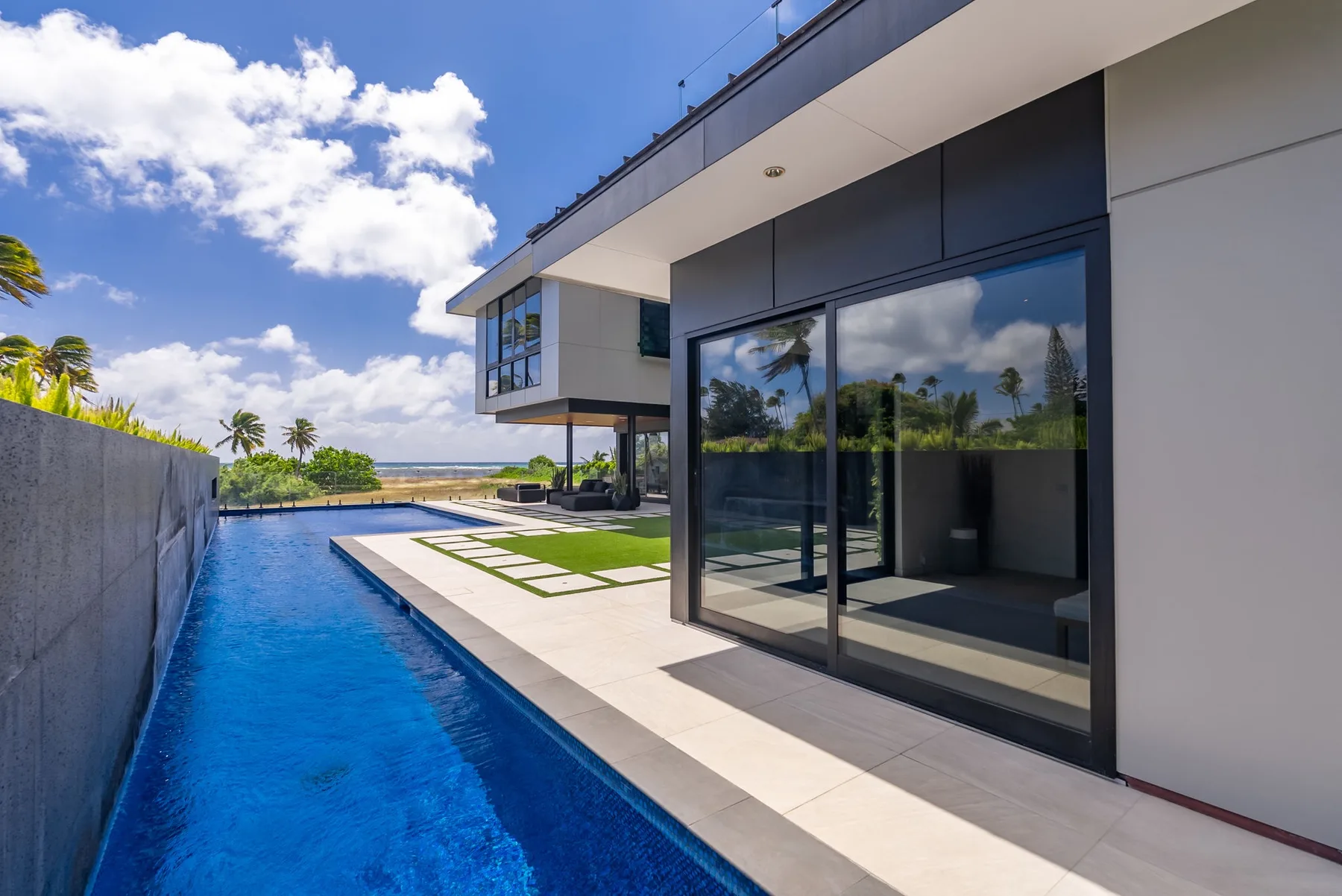 Una casa moderna da a una piscina larga y un patio pavimentado.
