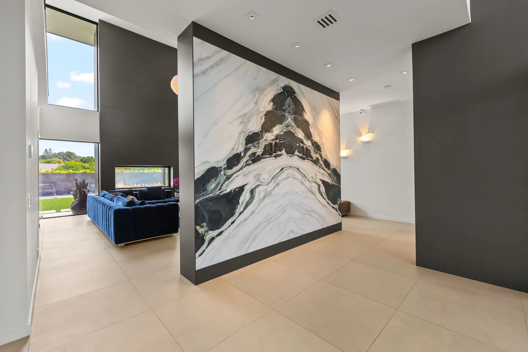 Un pasillo interior moderno cuenta con un gran panel de pared con vetas marmoleadas.
