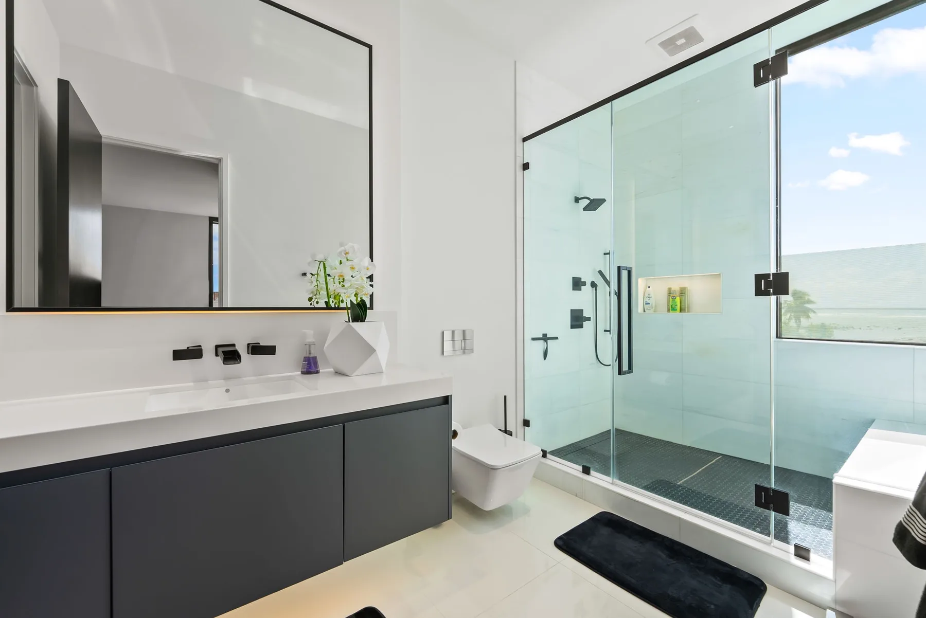 Un baño moderno con un amplio lavabo y una ducha con mampara de vidrio.