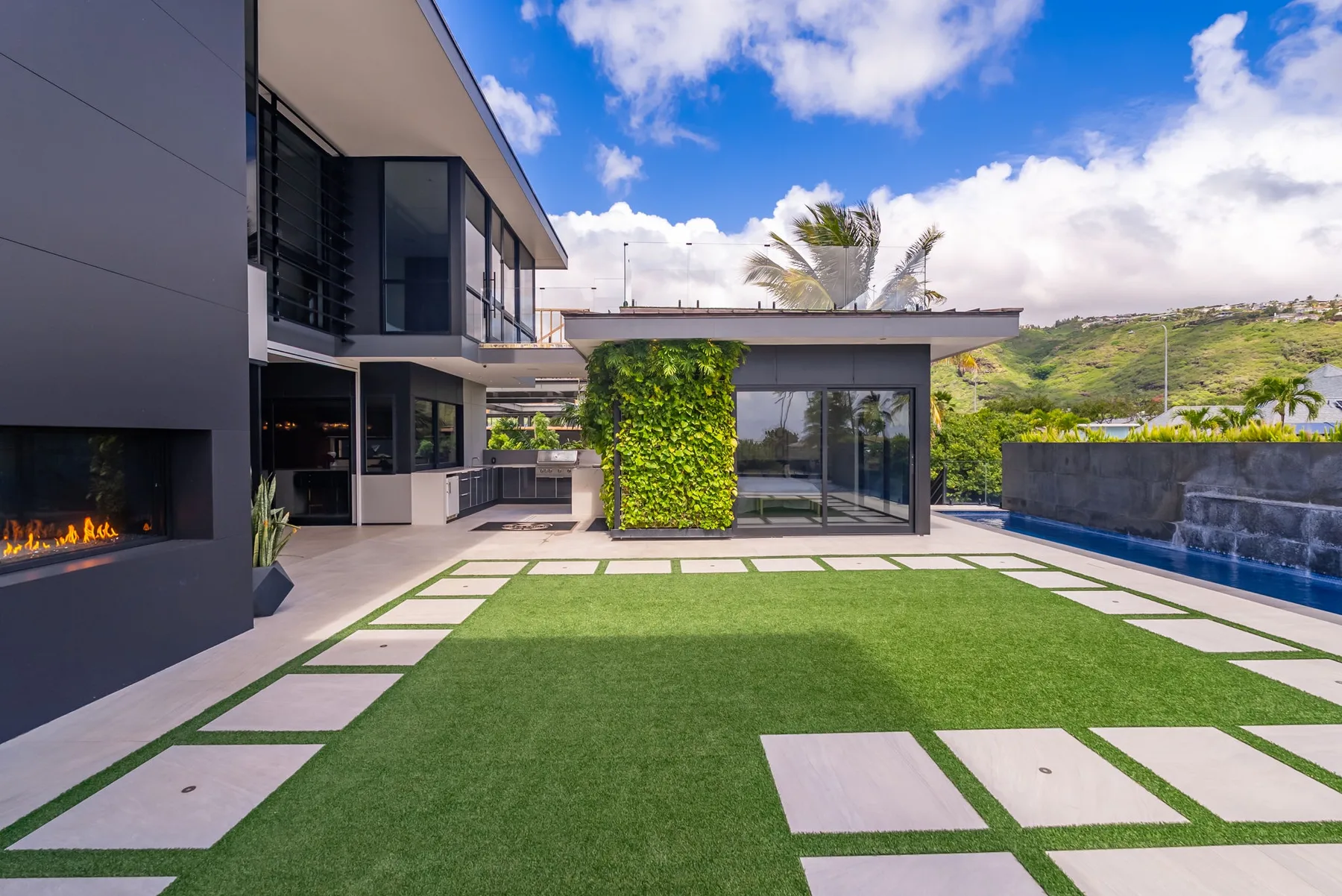 Una casa moderna da a un césped con piscina y puertas de vidrio.