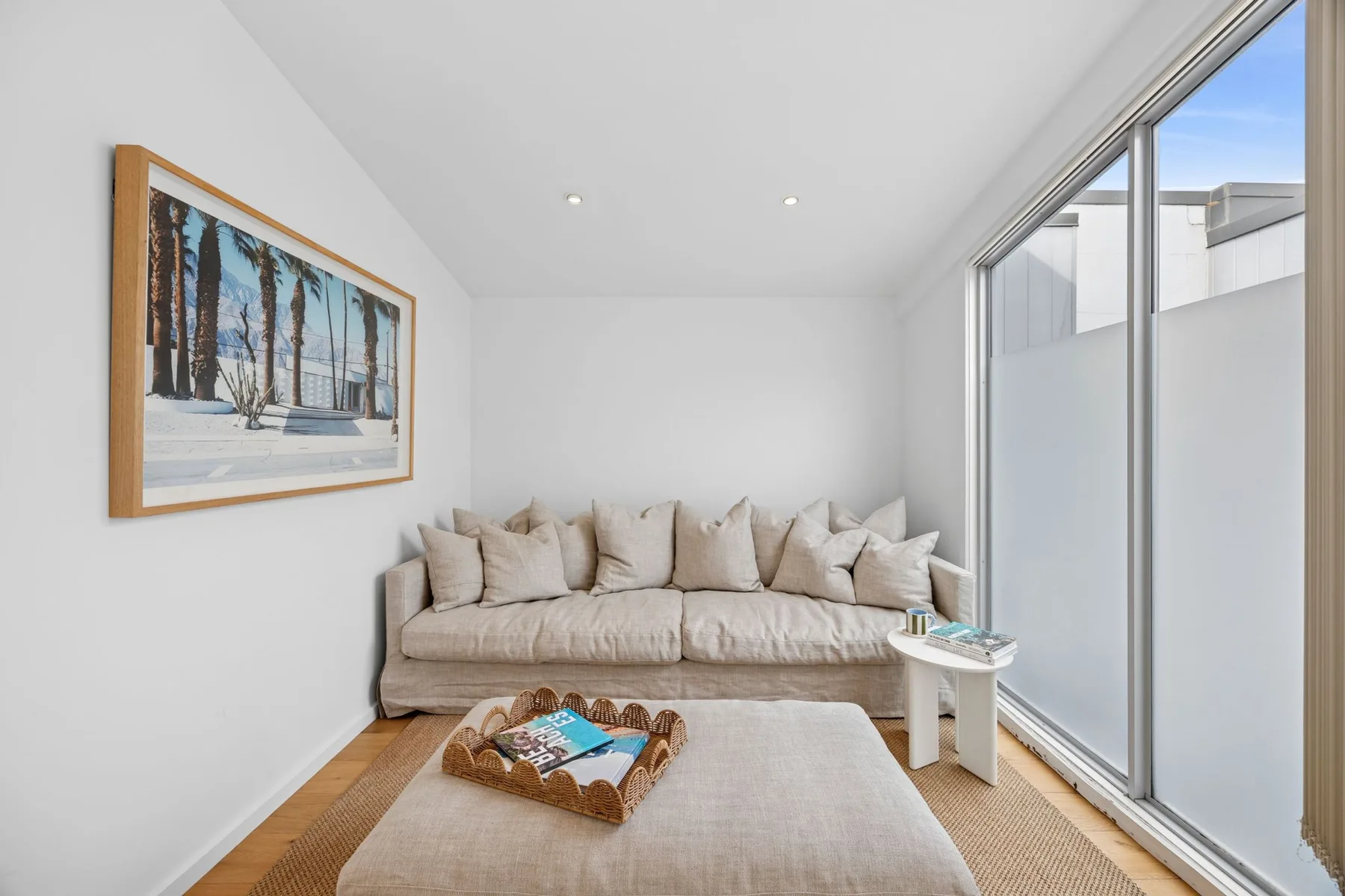 A bright living room has a beige seating area beside large windows.