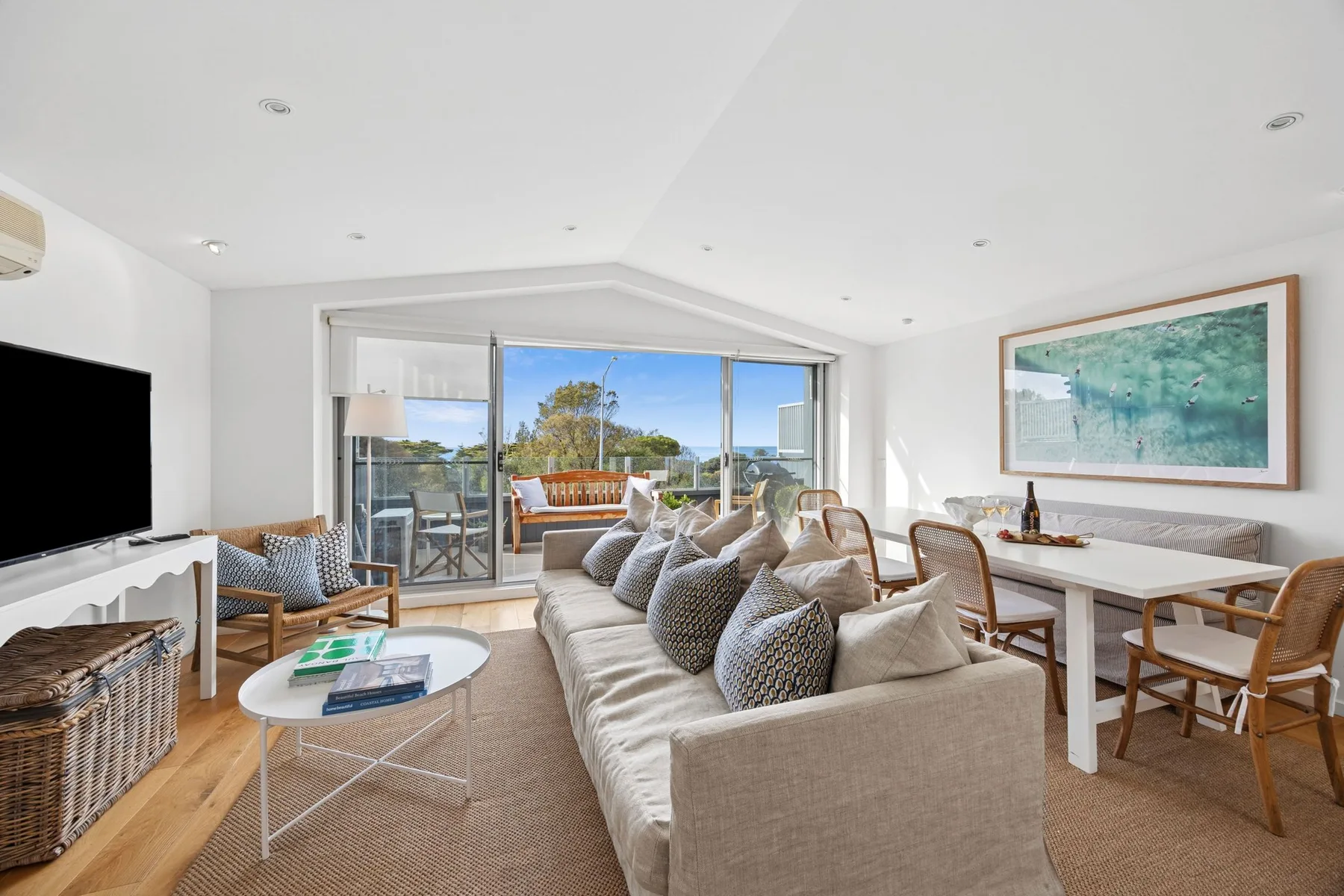 A bright living and dining area opens onto a balcony through large glass doors.