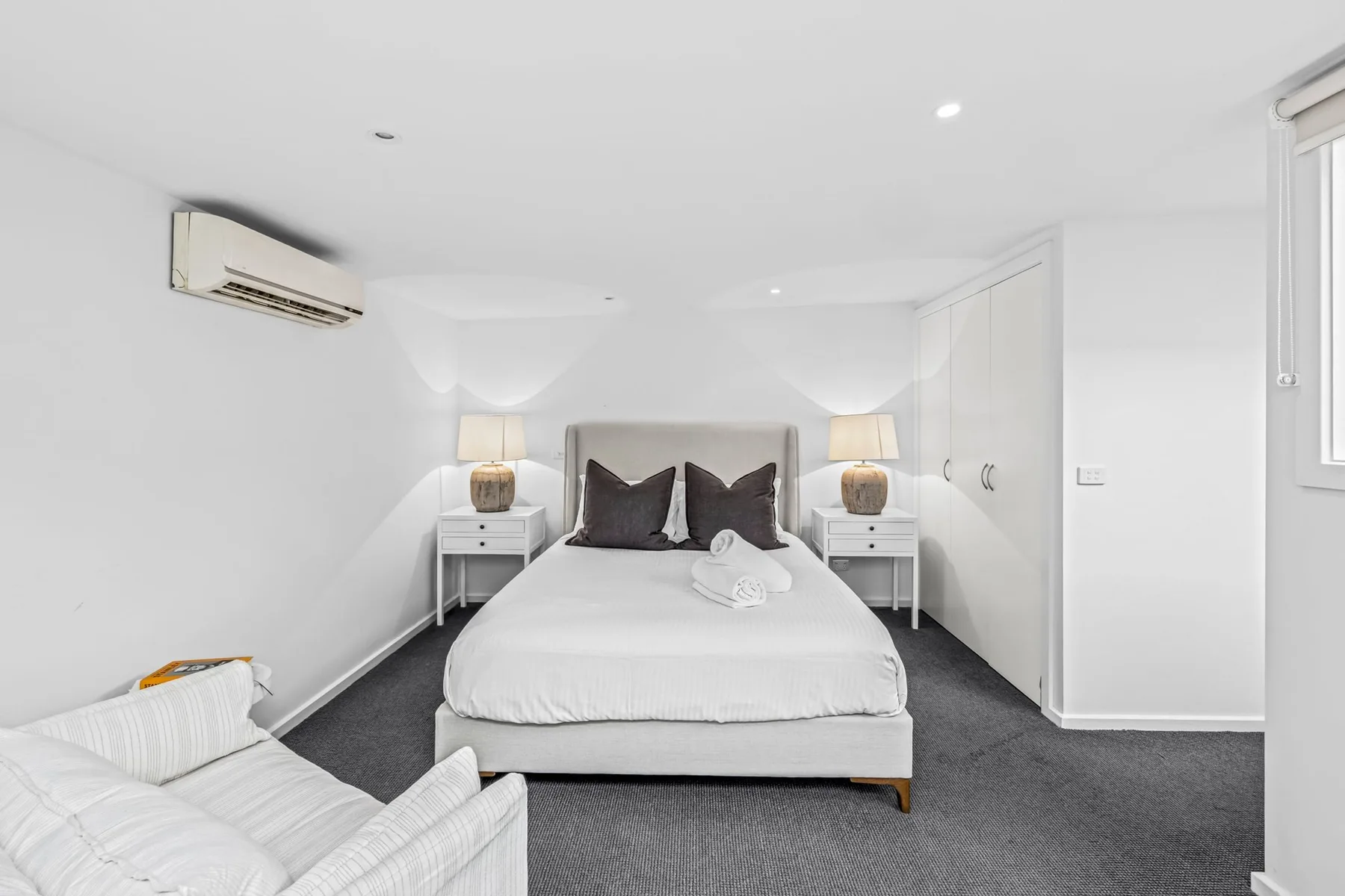A bright bedroom with a neatly made bed and bedside tables.