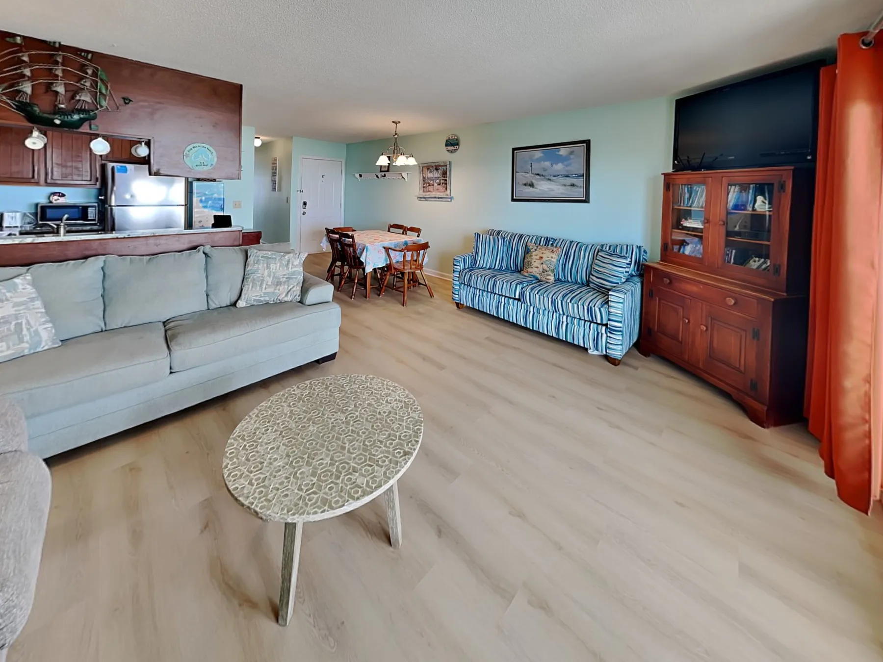 A living room with seating, a coffee table, and a dining area.