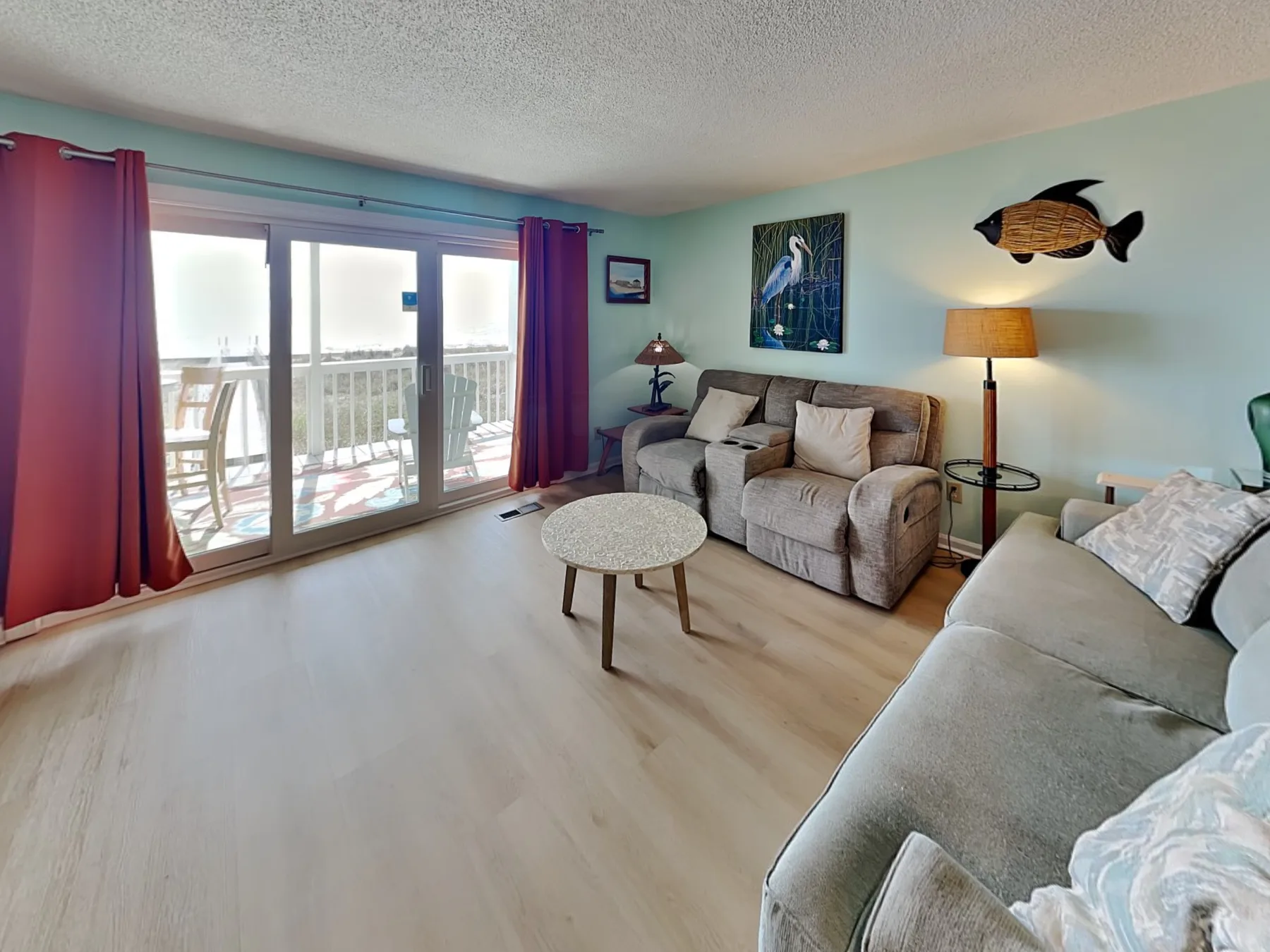 Sala de estar con asientos alrededor de una mesa de centro y puertas corredizas de vidrio.