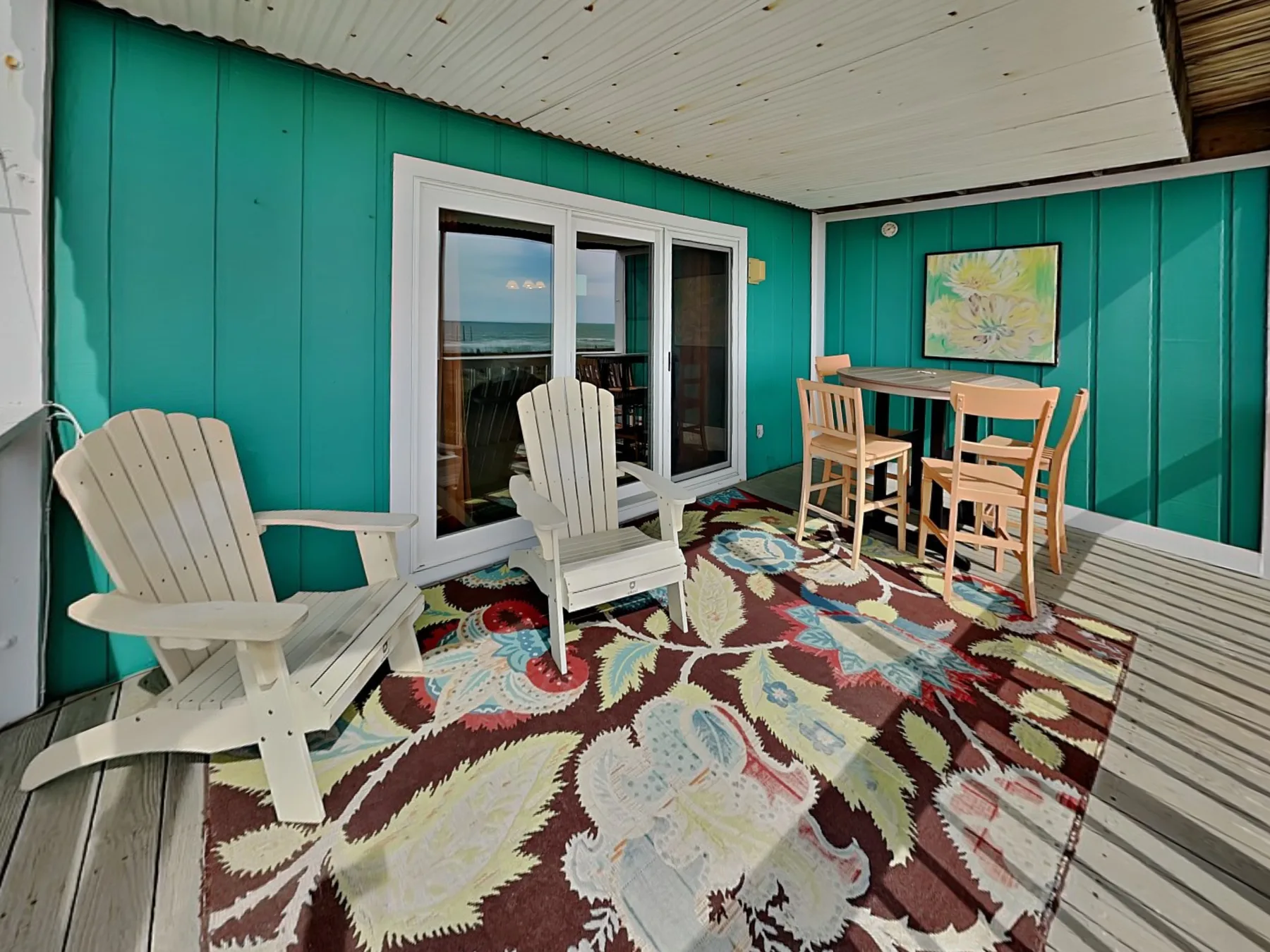 A covered patio with seating, a dining table, and a colorful patterned rug.