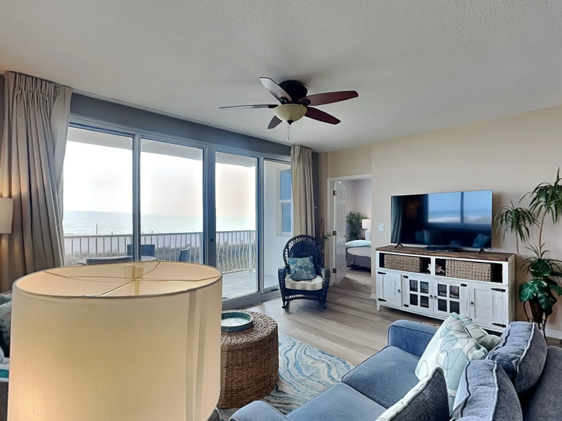 A living room with seating, a television, and sliding glass doors overlooking a balcony.