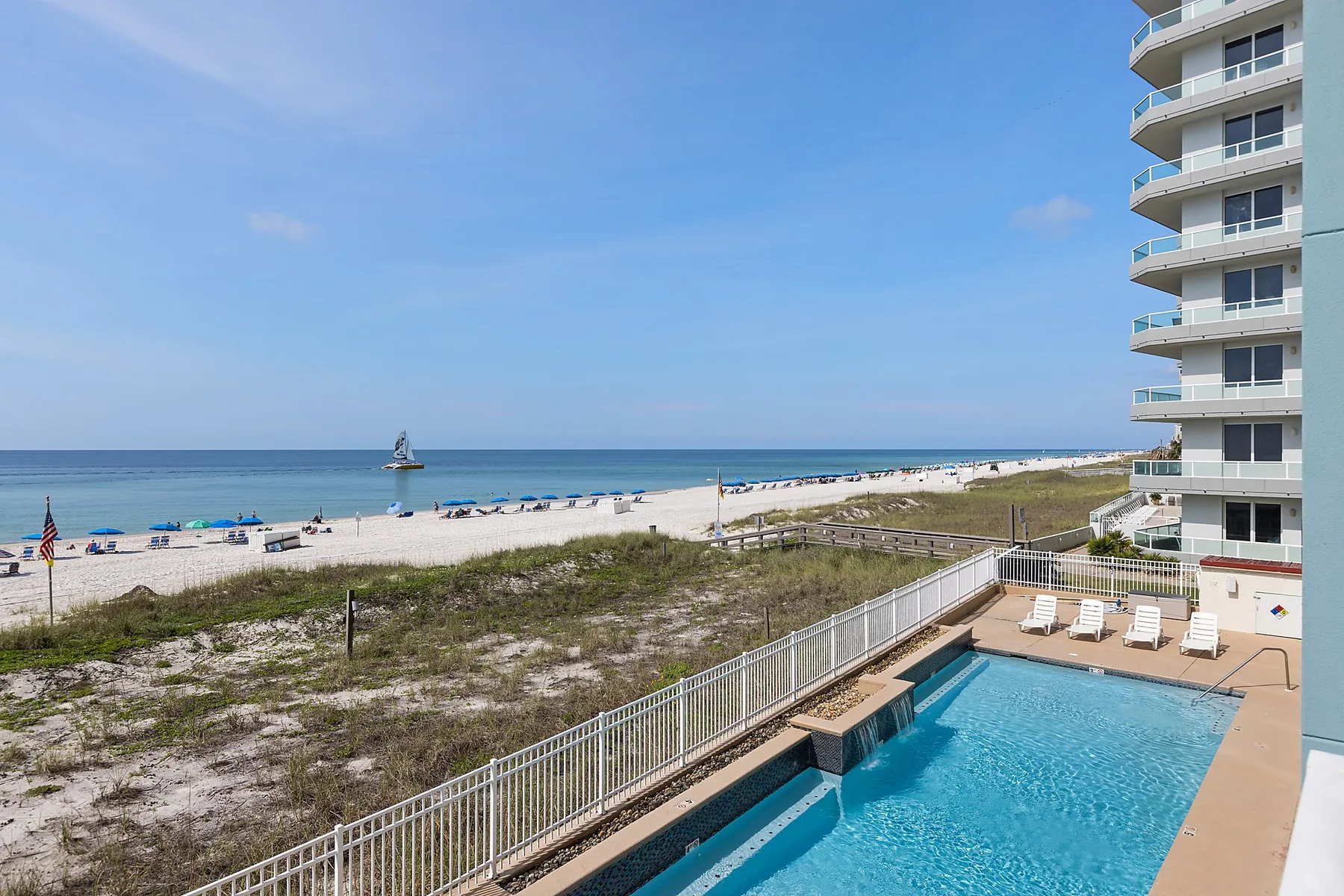 A beachfront pool overlooks sandy dunes and the ocean.
