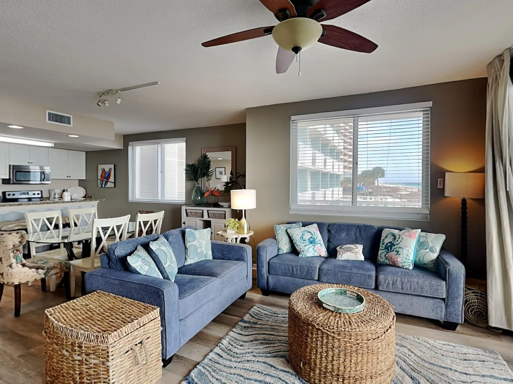 A living room with blue seating and woven baskets beside the dining area.