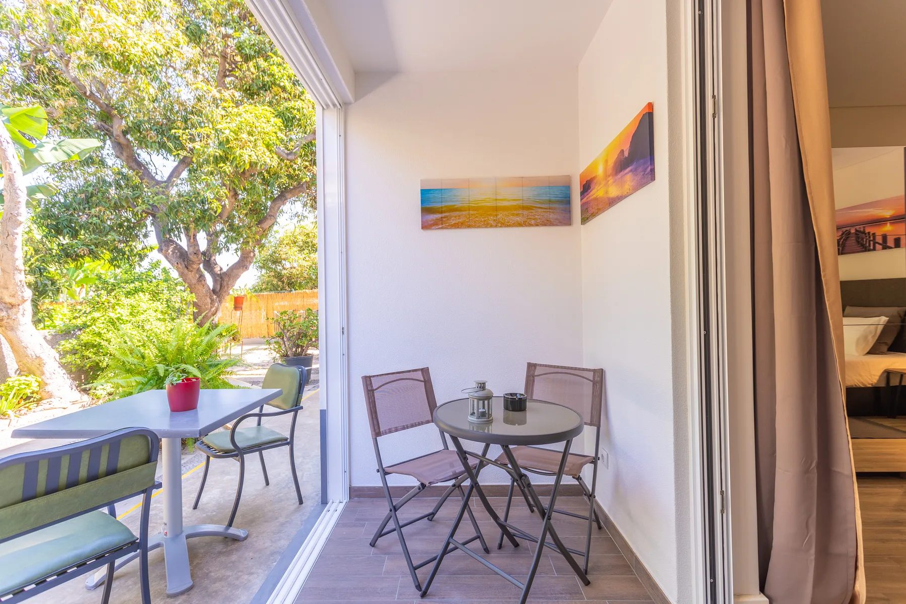 A dining area opens onto a garden patio with outdoor seating and greenery.