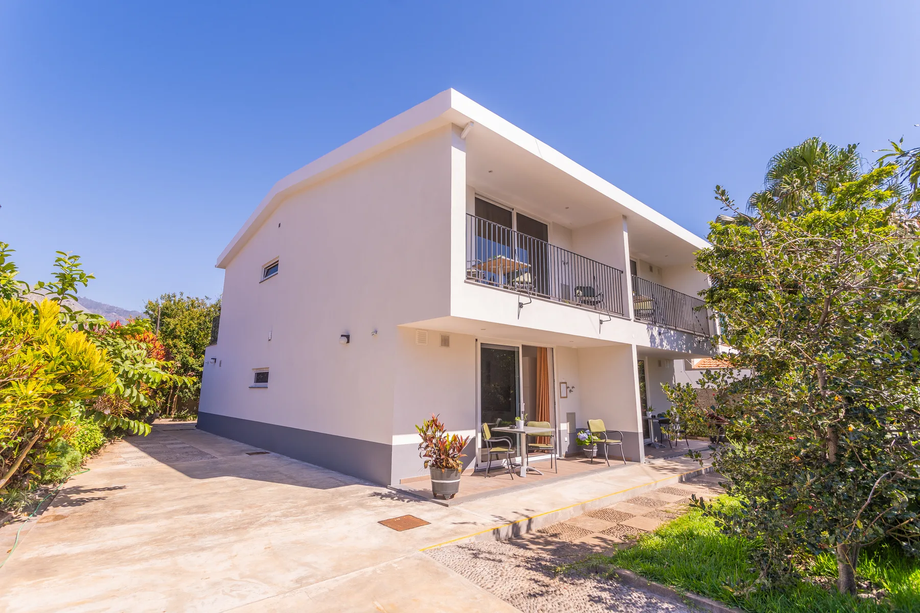 Modern two-story house with balconies and a paved patio.