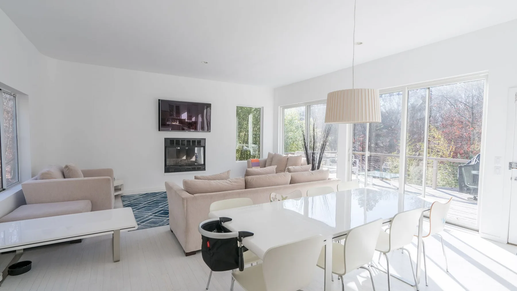 A bright living and dining area with seating, a table, and large windows.