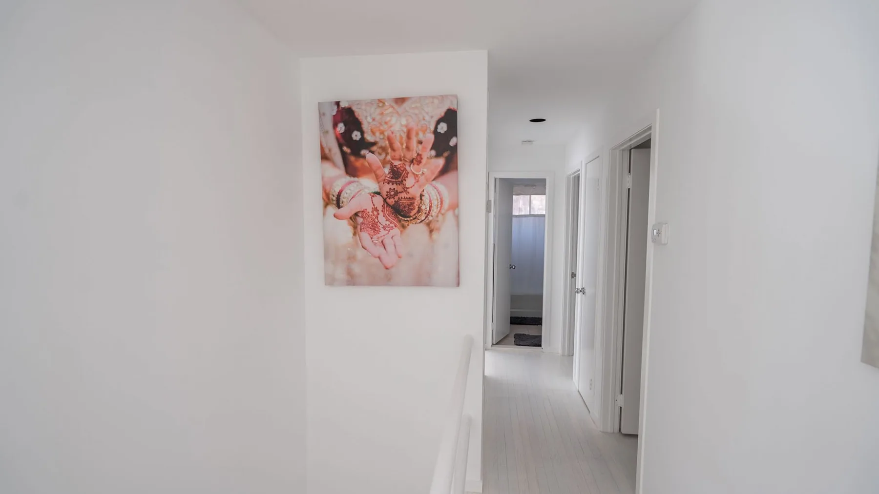 A bright white hallway with framed artwork on the wall.