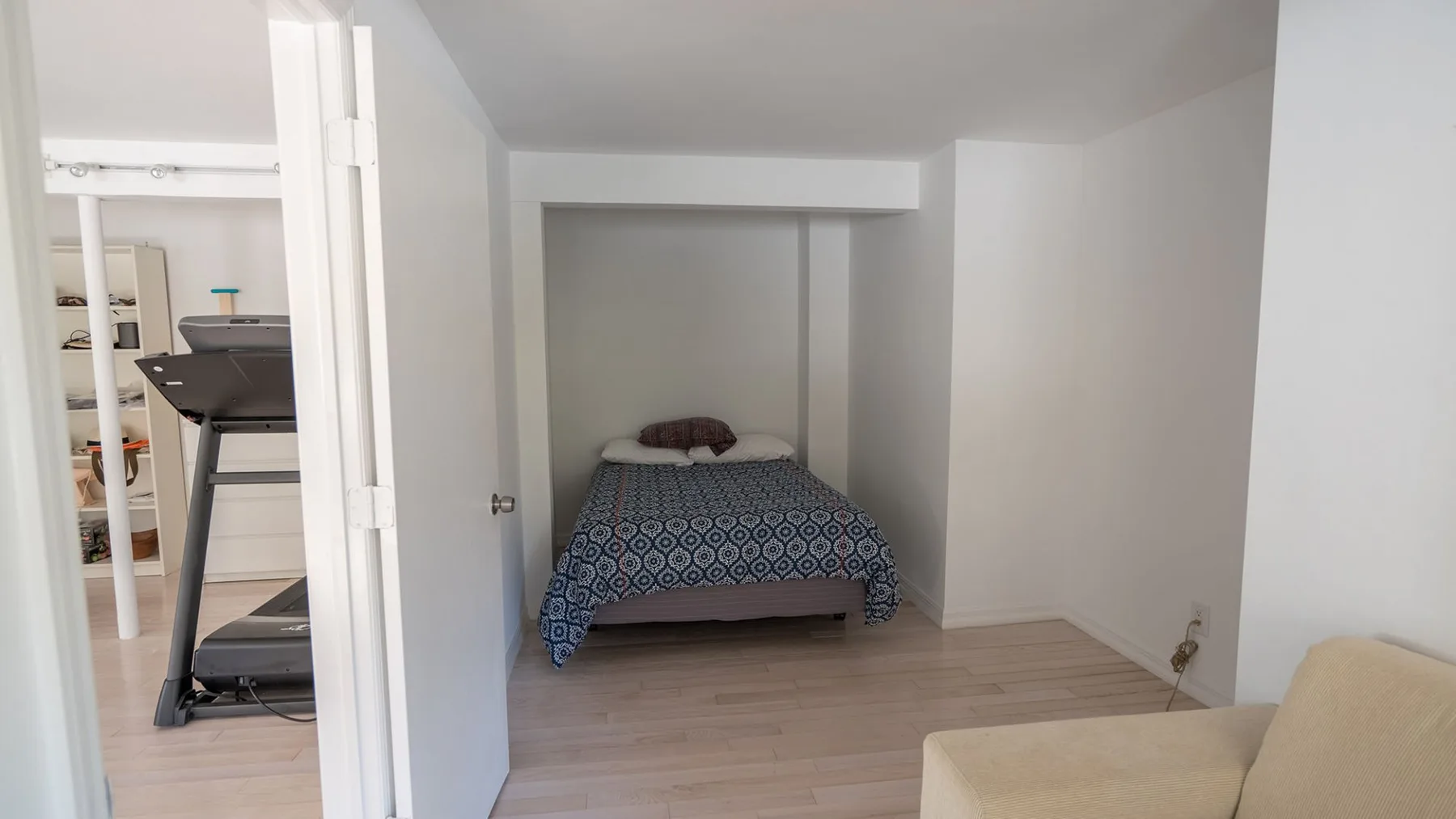 A compact bedroom with a bed and a light-colored seating area.