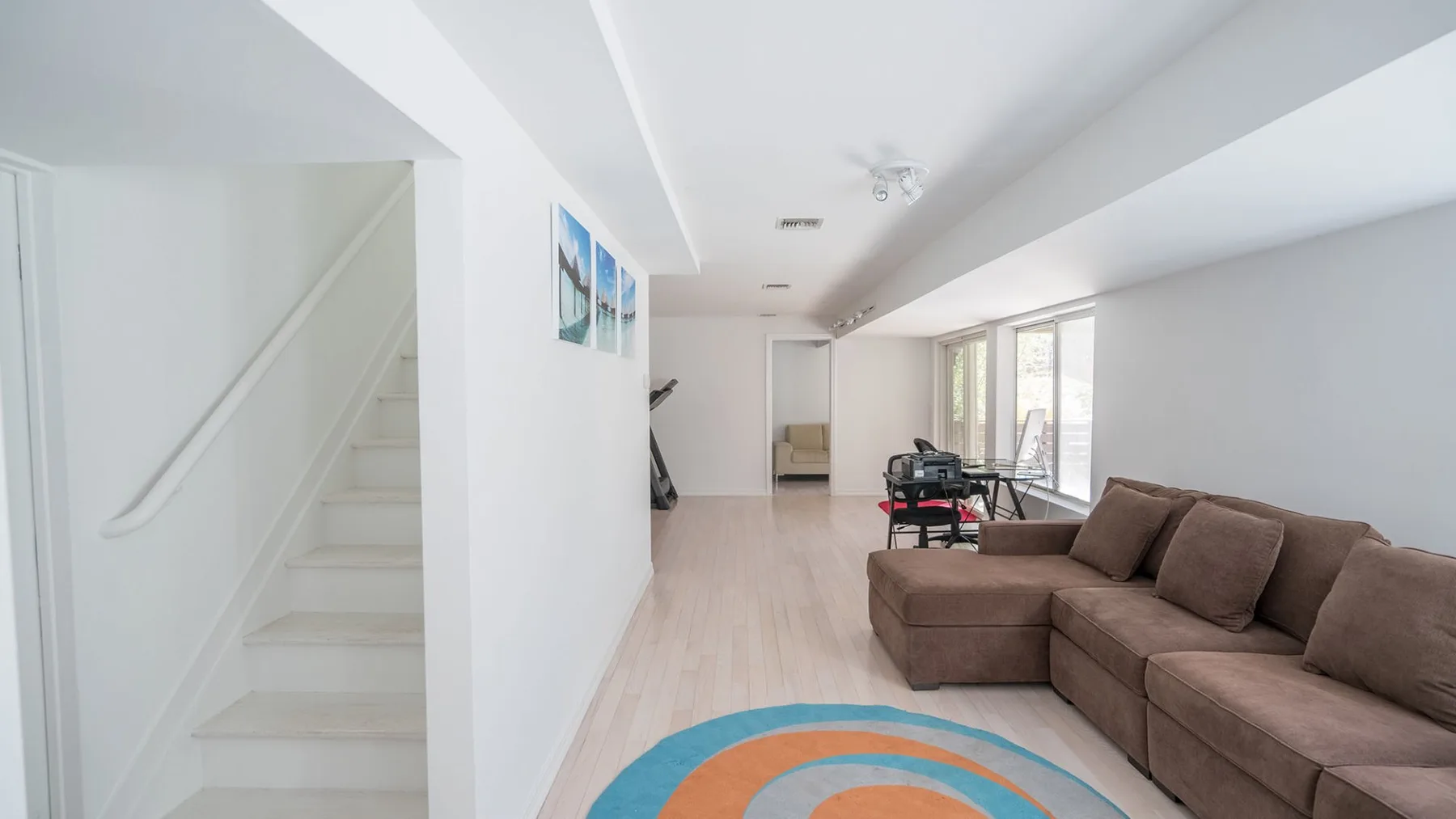 A bright living room with a sectional sofa and colorful round rug.