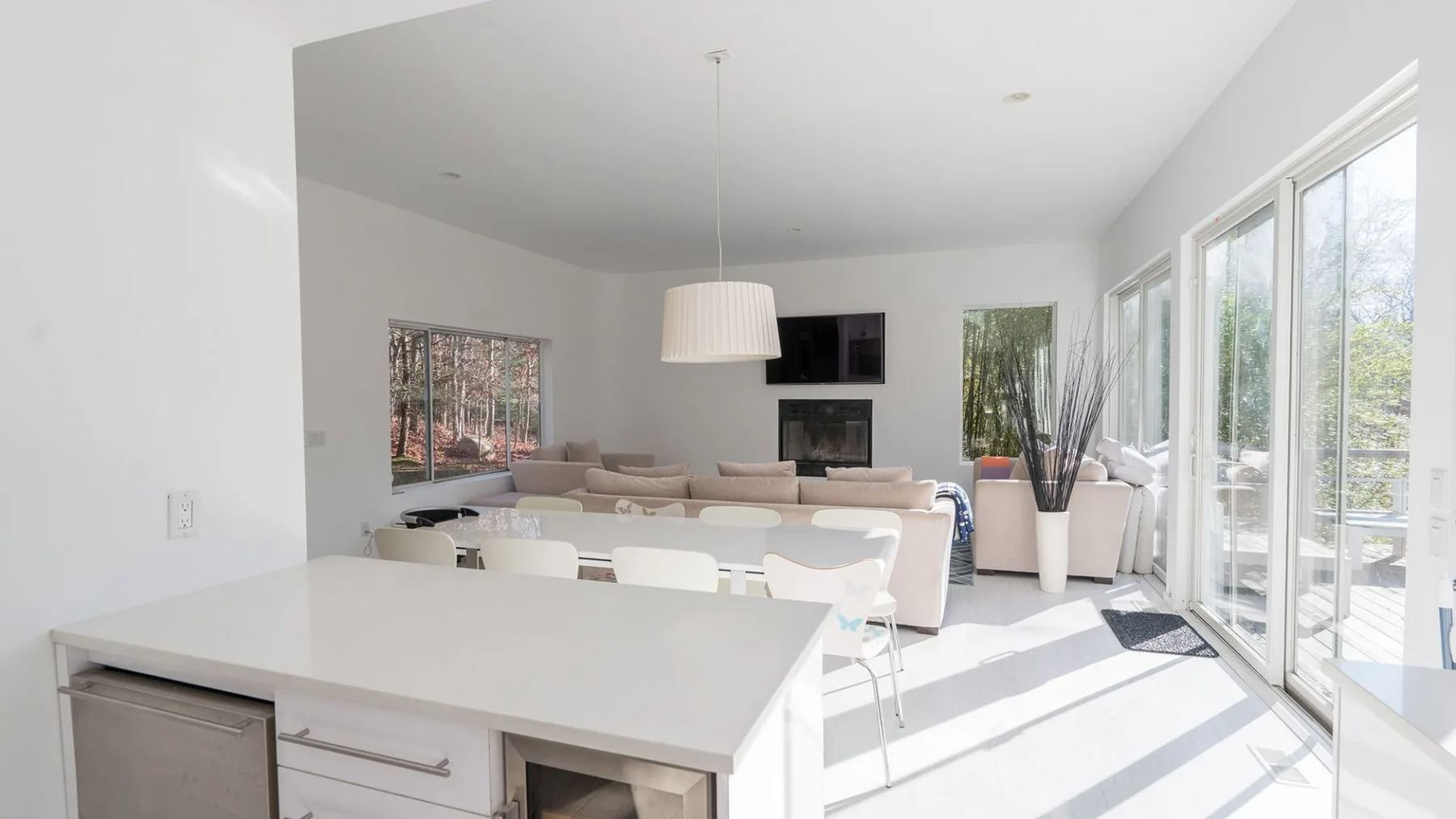A bright living room with seating, a television, and large windows.